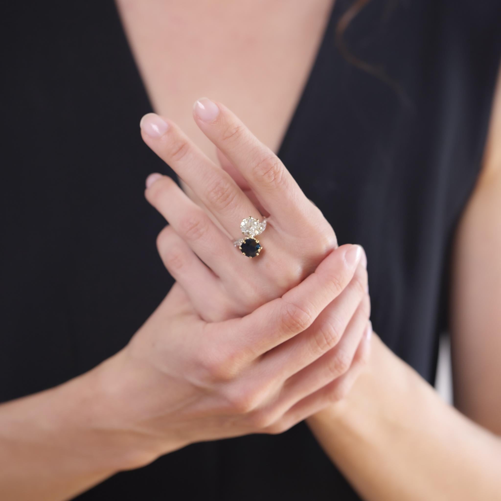 Este anillo victoriano de la década de 1880 presenta un diamante de talla europea antigua de 2,41 quilates, certificado por GIA (#2235567216) como de color N y claridad I1. Engarzado enfrente hay un zafiro talla cojín de aproximadamente 2,55