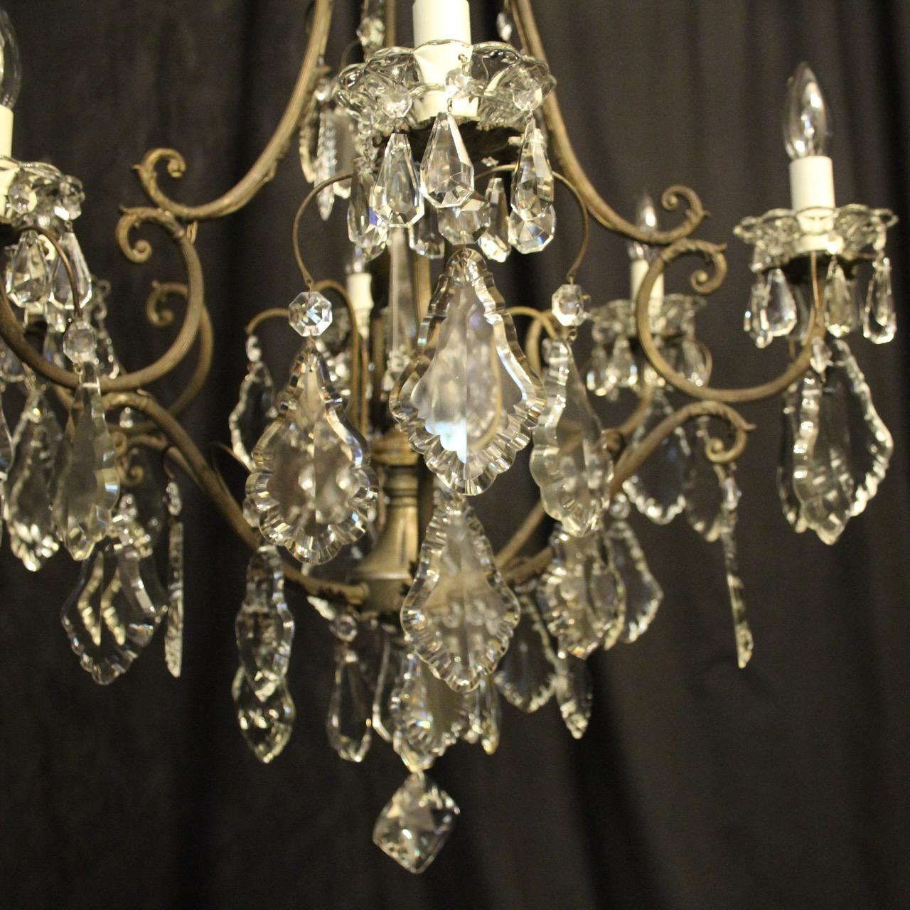 A French dark gilded brass and crystal 7-light birdcage form antique chandelier, the 6 reeded scrolling arms with glass bobeches drip pans, issuing from an foliated cage form interior with a single inverted light fitting and large prismatic spike