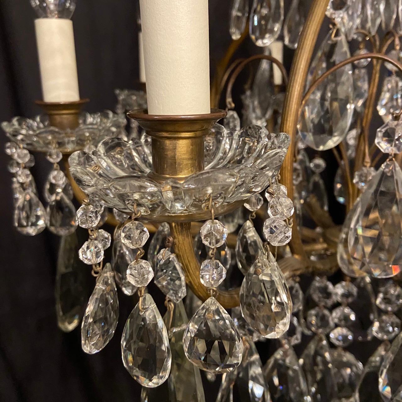 A French gilded brass and crystal 9-light birdcage form antique chandelier, the 8 reeded scrolling arms with glass bobeche drip pans and candle sconces, issuing from a foliated cage form interior with a single inverted light fitting and wirework