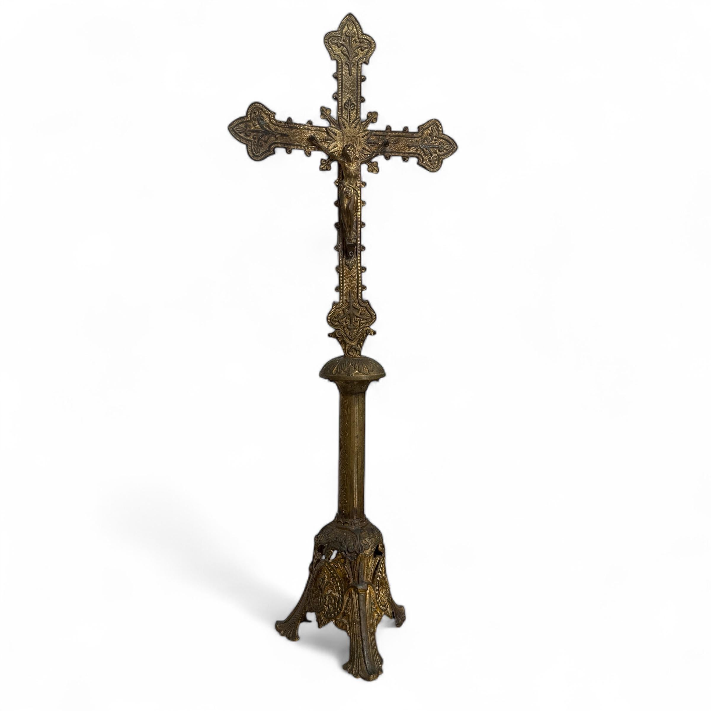 An 19th-century French altar crucifix crafted in richly gilded bronze. This ecclesiastical piece stands on a tri-lobed base, each panel featuring a finely detailed medallion representing the Holy Trinity, a rare and symbolic motif. The cross itself