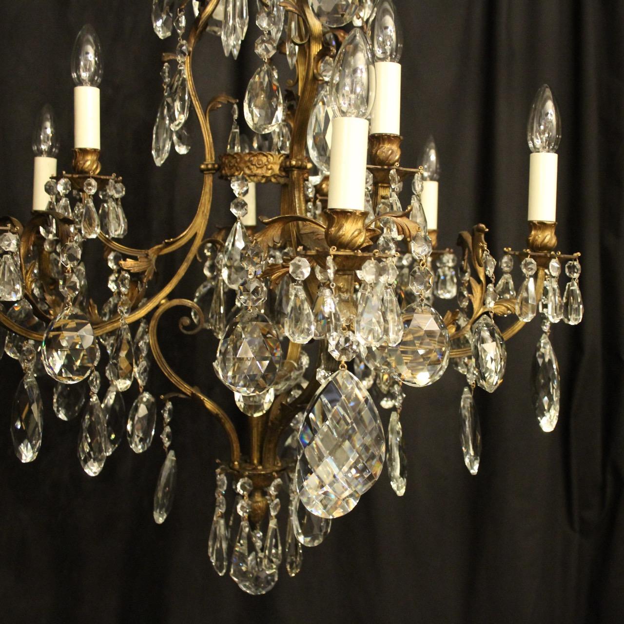 A French gilded bronze and crystal 10 light birdcage form tiered antique chandelier, the square gauge leaf clad reeded scrolling arms with sectional bobeche drip pans and leaf candle sconces, issuing from an foliated cage form interior with a single
