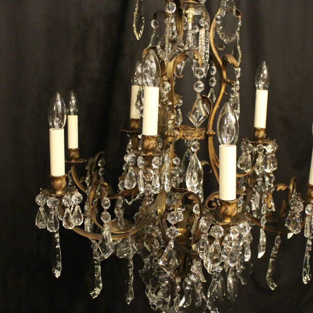 A French gilded cast bronze and crystal 13 light birdcage form tiered antique chandelier, the square gauge leaf clad reeded scrolling arms with ornate bobeche drip pans and leaf candle sconces, issuing from an foliated cage form interior with a