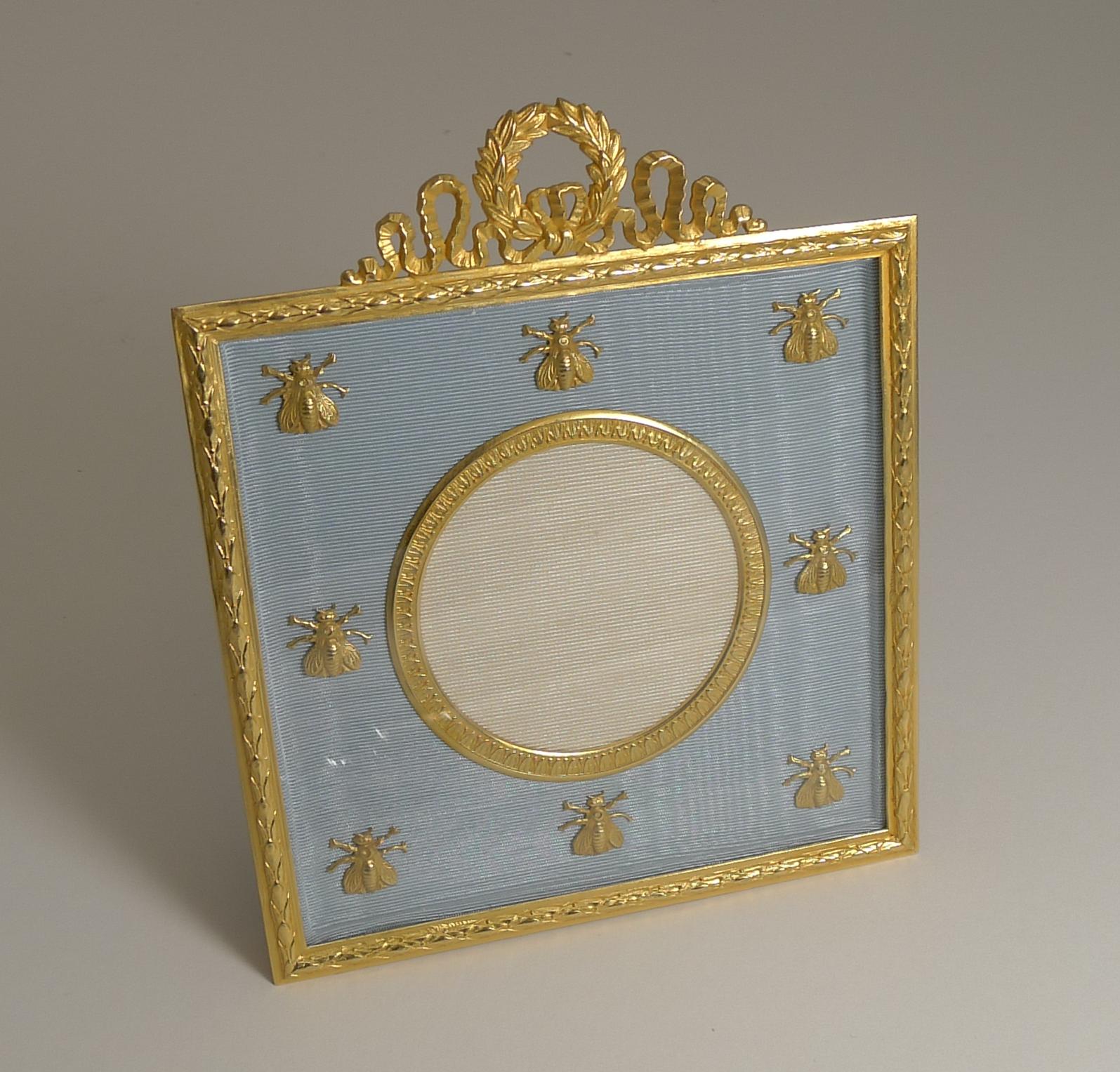A charming and highly decorative photograph frame made from Ormolu or gilded bronze; the silk taffeta mounted with a series of gilded bronze Napoleonic bees protected with a glass front.

Professionally restored to it's former glory, the frame is