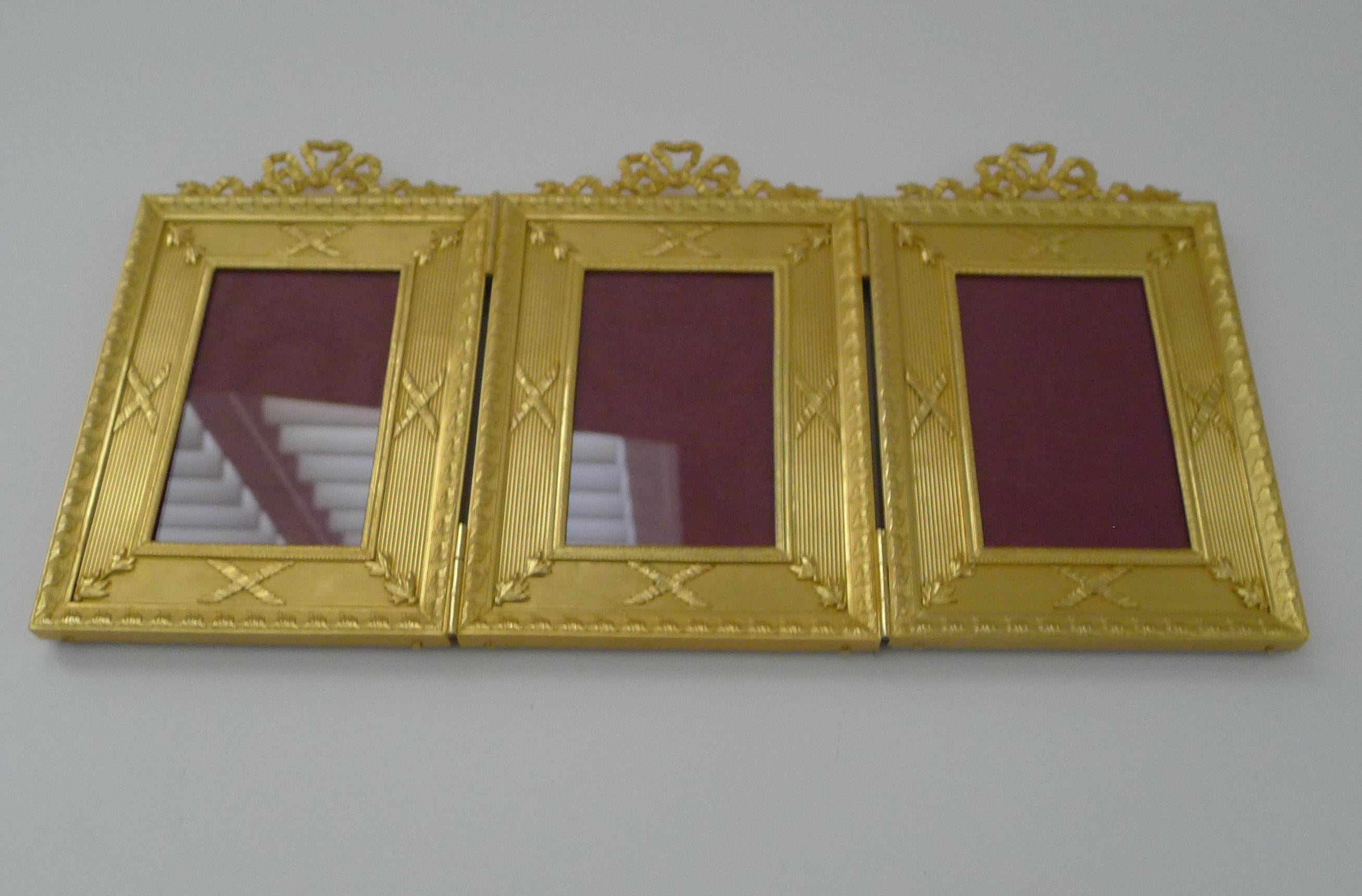A stunning antique French gilded bronze triple picture frame, professionally restored to it's former glory.

The three hinged frames are made from hefty cast bronze and lavishly finished in gold, showcasing their beautiful design and ribbon and bow