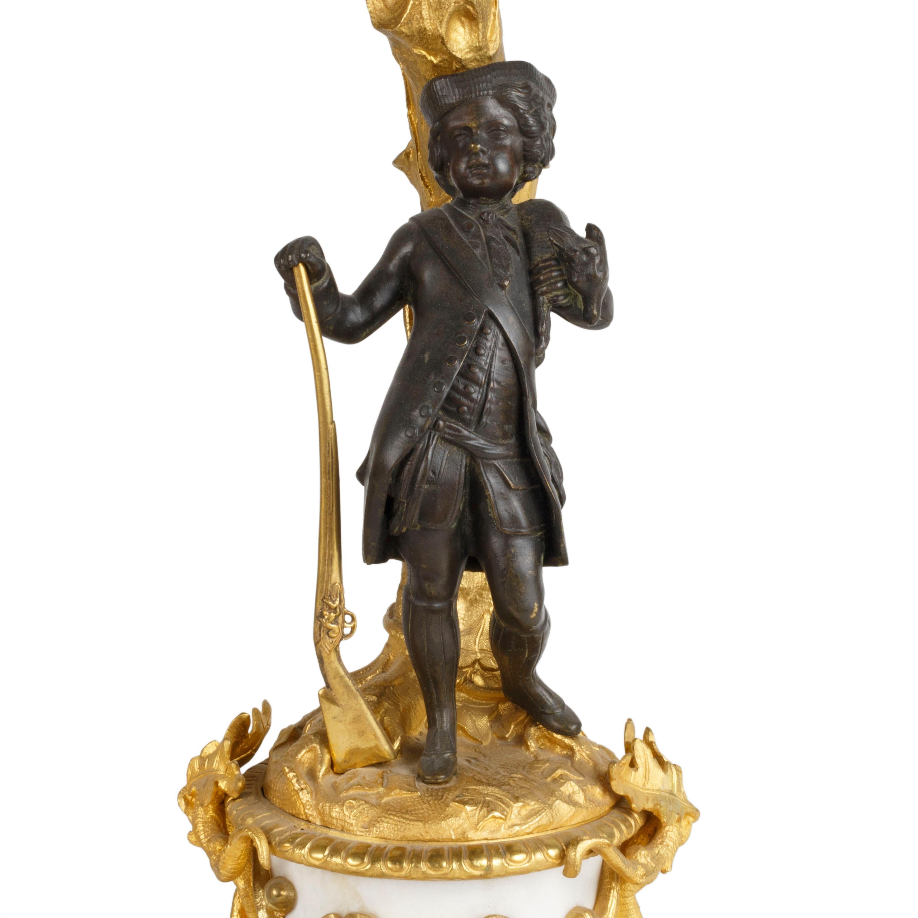 Pair of French gilded candelabras. Matched pair except one having a male hunter in bronze at base and the other a female hunter in bronze at base. In the style of Henri Picard. Marble, solid bronze, 24-karat gold gild. Measures: 17