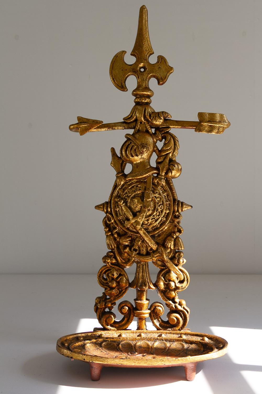 Portaombrelli francese in ghisa dorata, anni '50.

Portaombrelli o bastoni in ghisa in stile vittoriano. 
Supporto decorativo e ornato dipinto in oro che raffigura un elmo di cavaliere con scudo e spada. Vassoio di raccolta con motivo a forma di