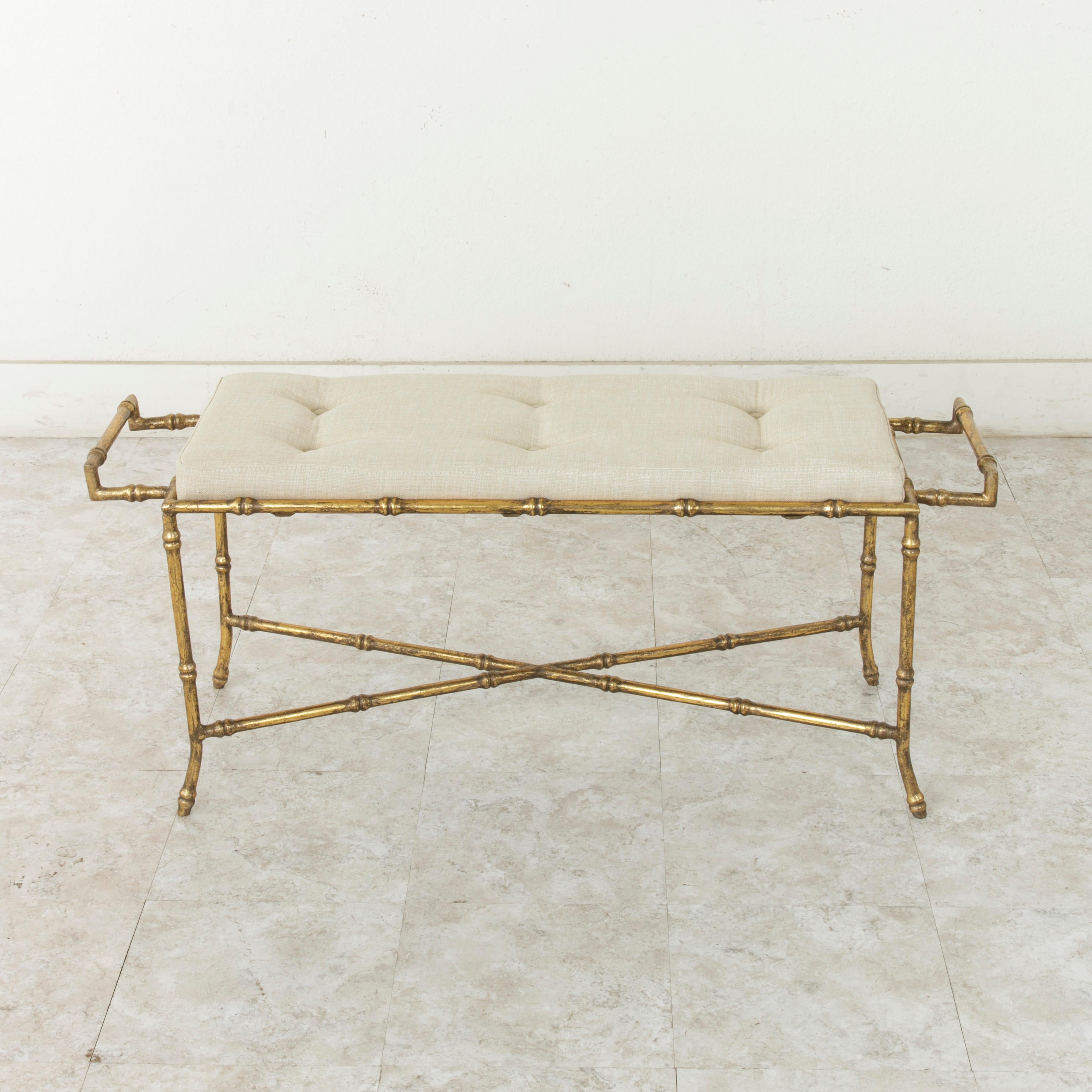 An original creation by a contemporary French designer, this gilded iron banquette or bench features a faux bamboo aesthetic with an X stretcher at the base and a handle at each end. Newly upholstered in France in linen with button detailing.
   
