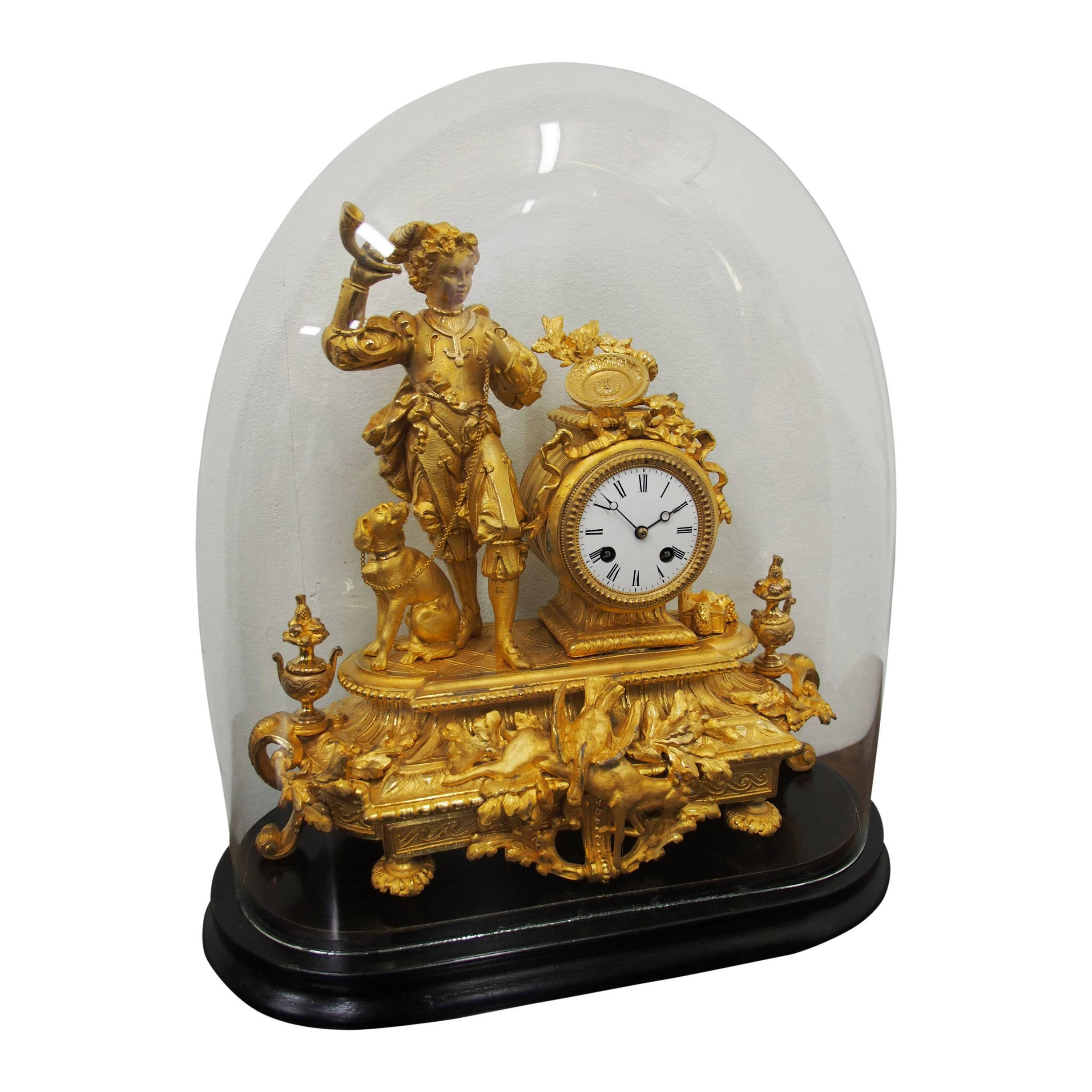 French gilded mantle clock, circa 1870. Depicting a young boy with a horn in his hand and a dog on a leash, and with a circular clock with white enamel face and Roman numerals. It is encased in a profusely cast casing with ribbons and beading at the