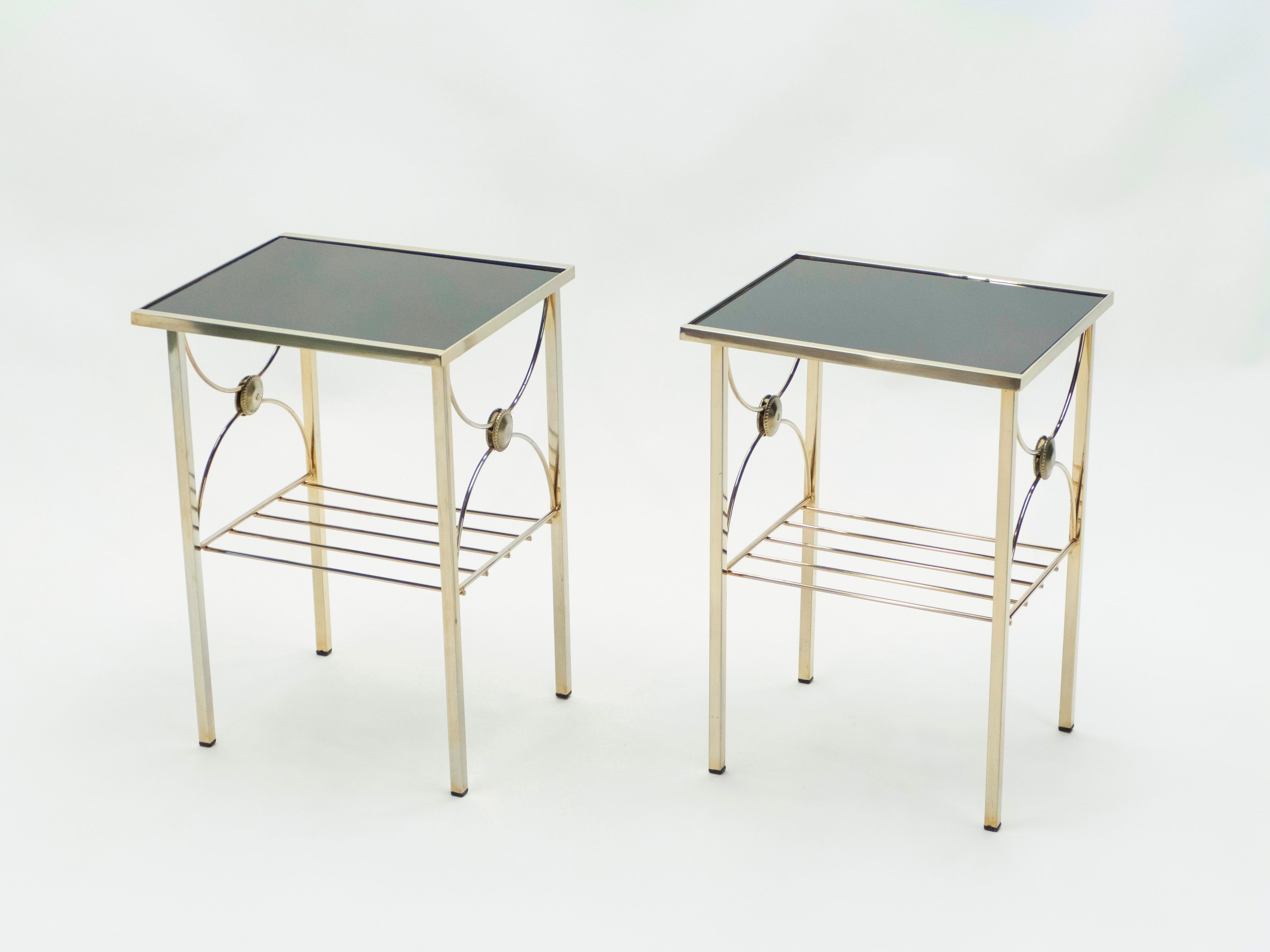 Simple lines point to these two-tier end tables french midcentury roots. Designed and produced in France in the early 1960s, it features silky brass legs and structure with black oplaine glass tops. Its symmetry, elevated glass, and strong