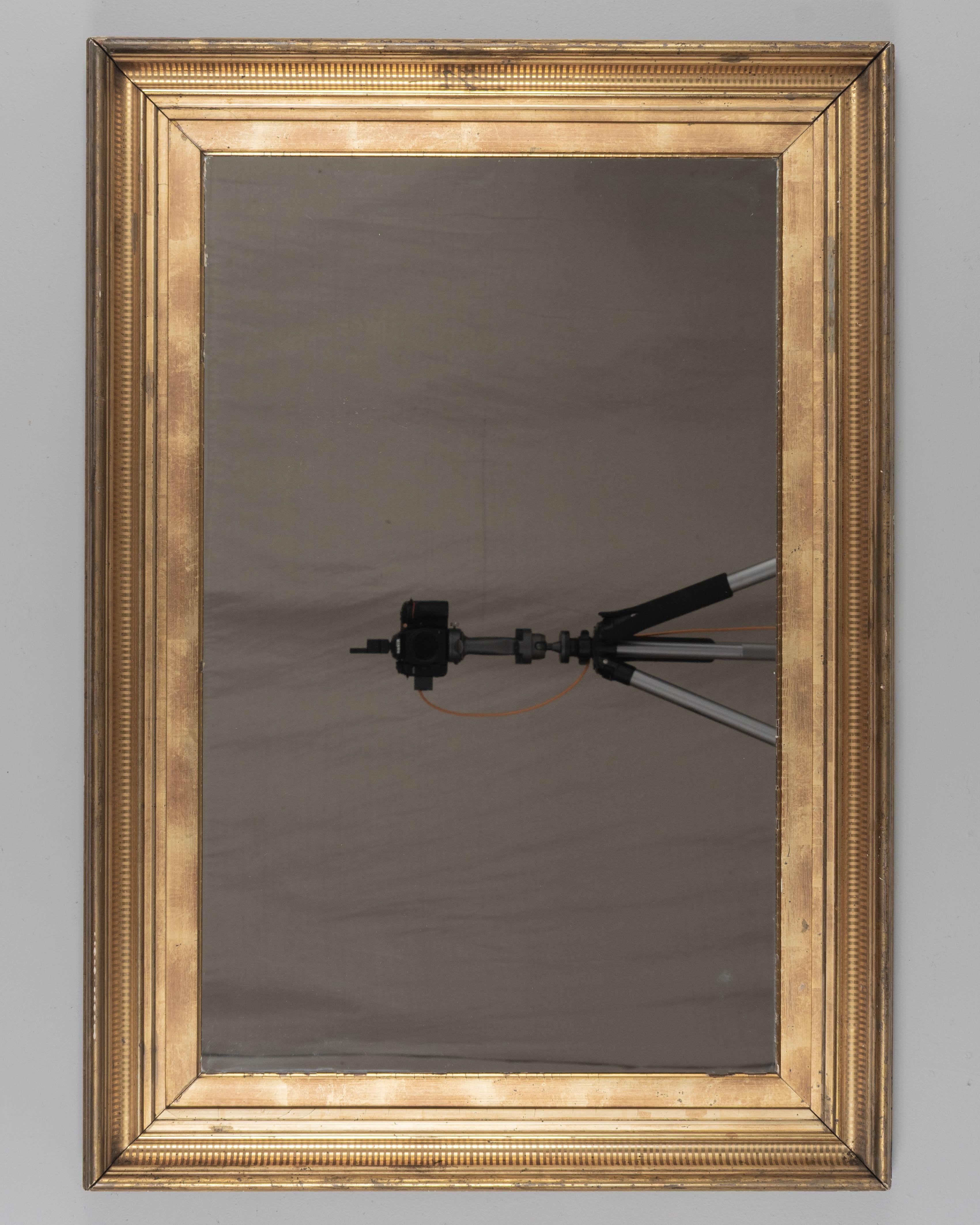 A French gilded mirror with incised decoration. Frame has bright gilt with minor losses, slight corner separation. Original mirror is in good condition. Wired to be hung horizontally, but may be hung vertically. Please refer to photos for more