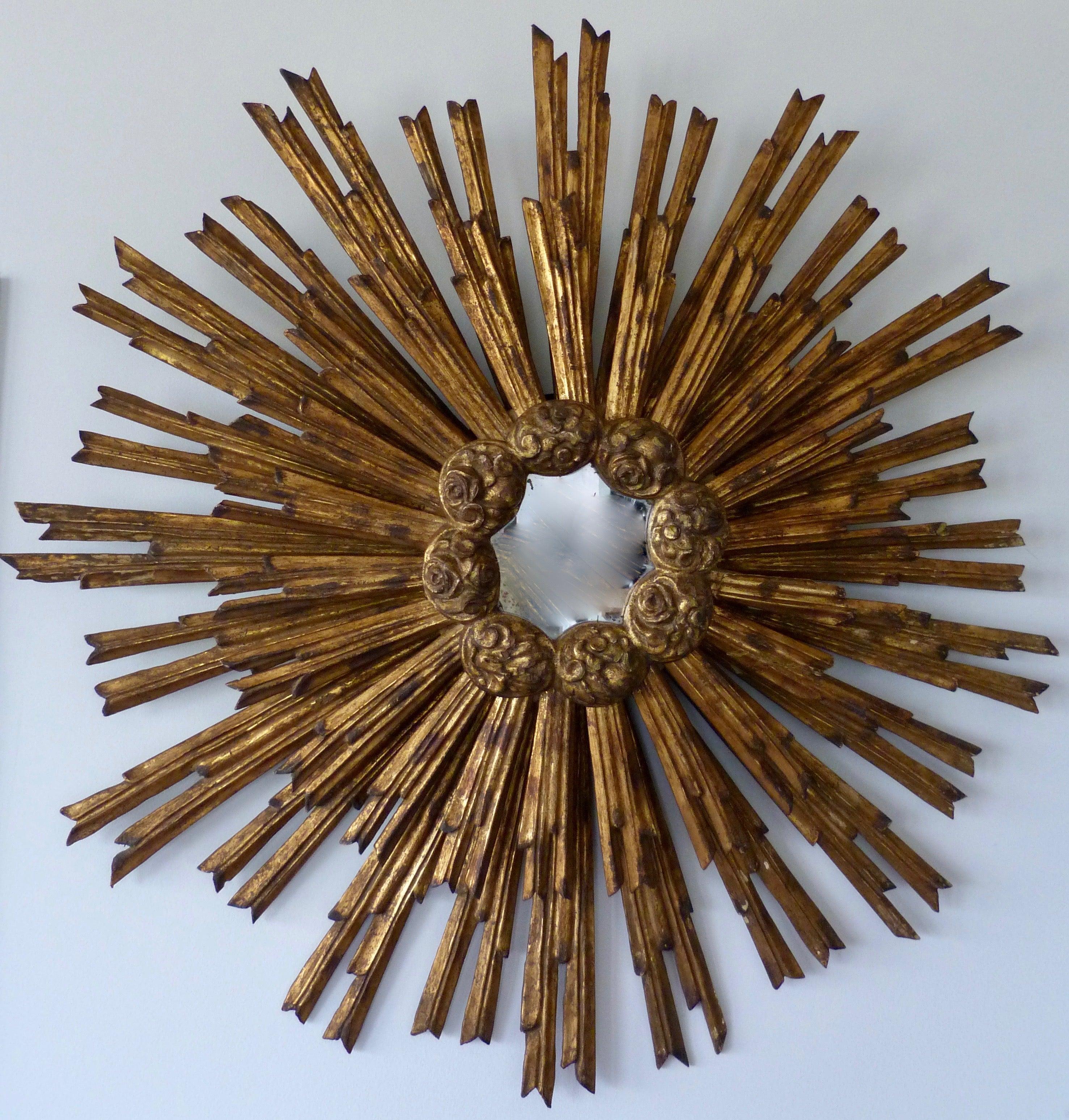 A French gilded sunburst mirror, second half of the 19th century.

Made of 2 overlapping Sunburst parts joined together with carved flower buds around the middle rim.