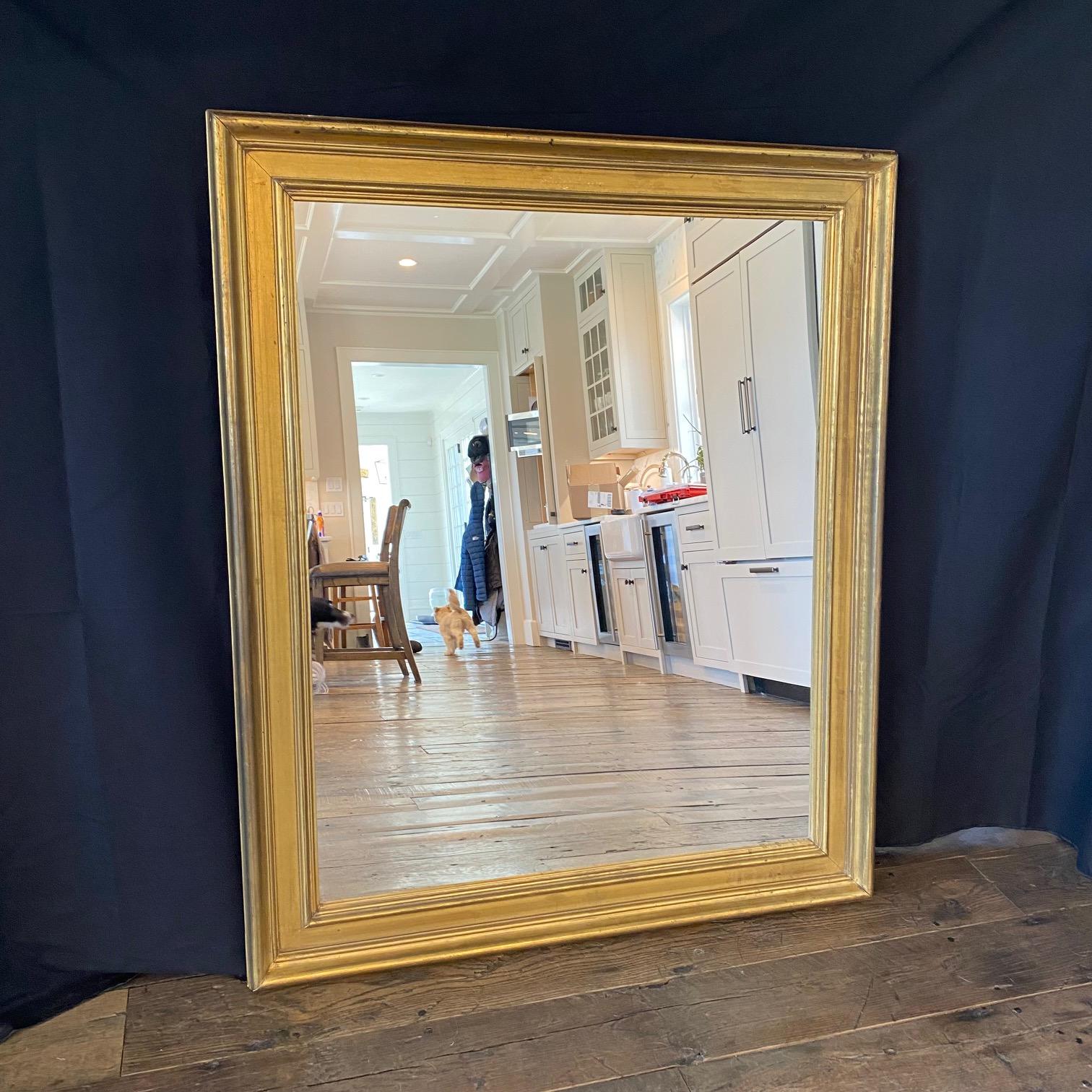 Atractivo espejo de pared rectangular dorado francés que presenta un borde moldeado en relieve y profundamente detallado alrededor de la circunferencia y una encantadora pátina cálida de pan de oro. Listo para colgar - Se puede exponer vertical u