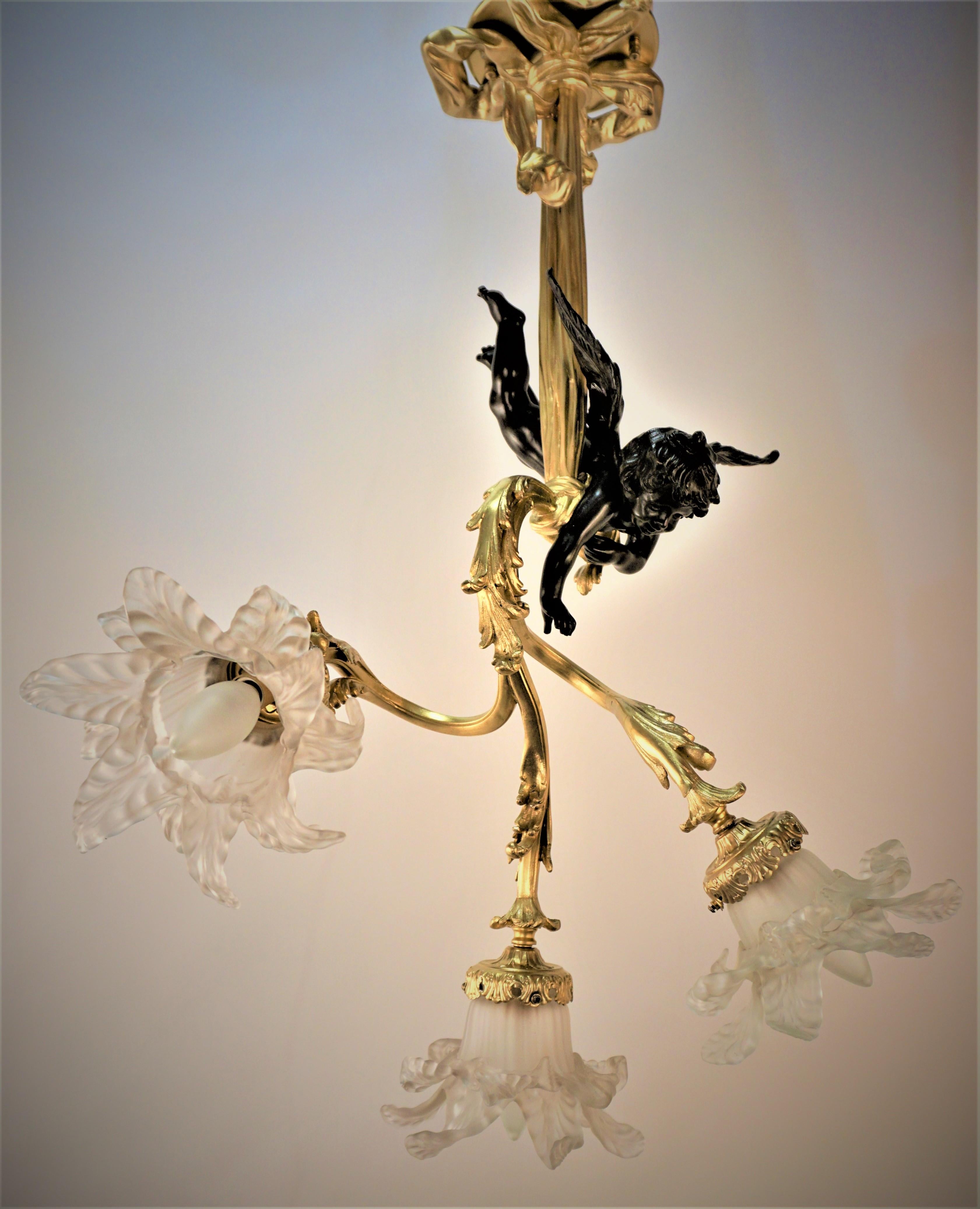 Gilt and bronze, patinated bronze cherub holding branches with hand blown glass flora shades.
Professionally rewired and ready for installation.
