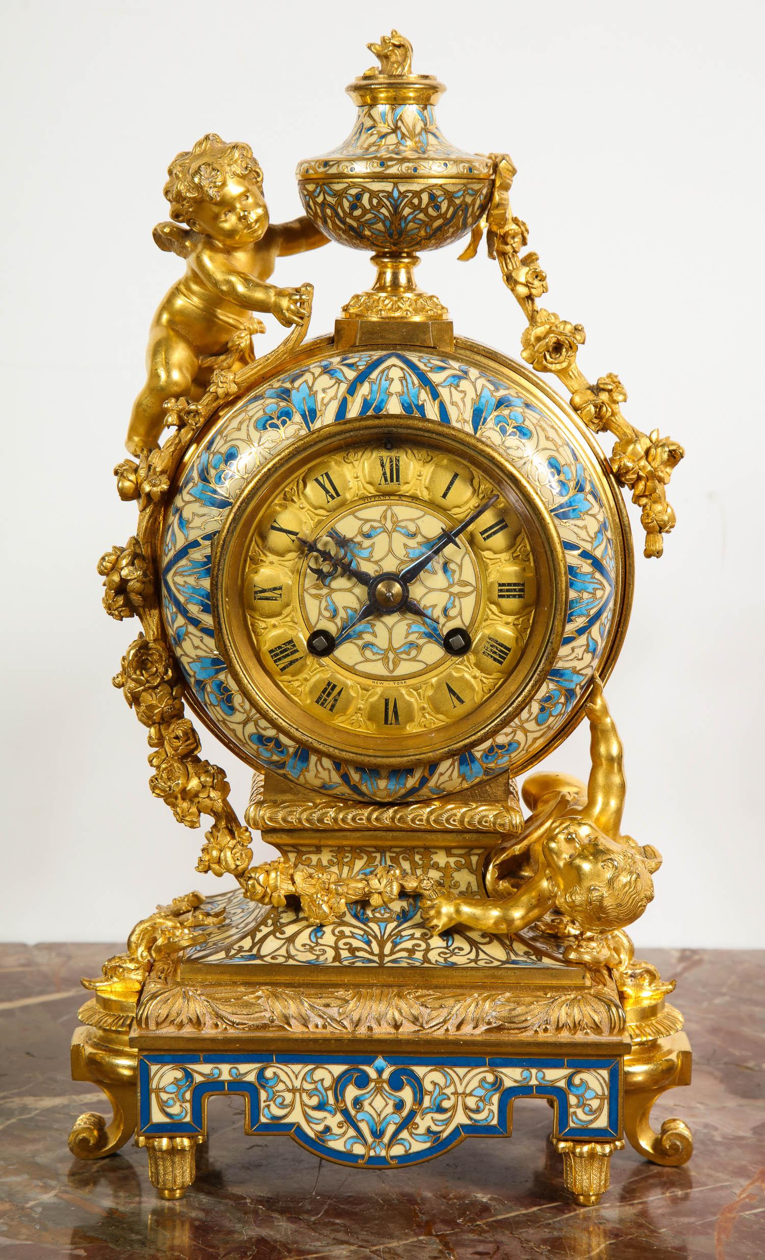 Pendule à trois pièces en bronze doré et émail de Champleve,
Retaillé par Tiffany & Co, vers 1890.

Comprend une horloge avec putti et une paire de chandeliers avec putti.

Bonne qualité. Le cadran et le mouvement de l'horloge sont marqués