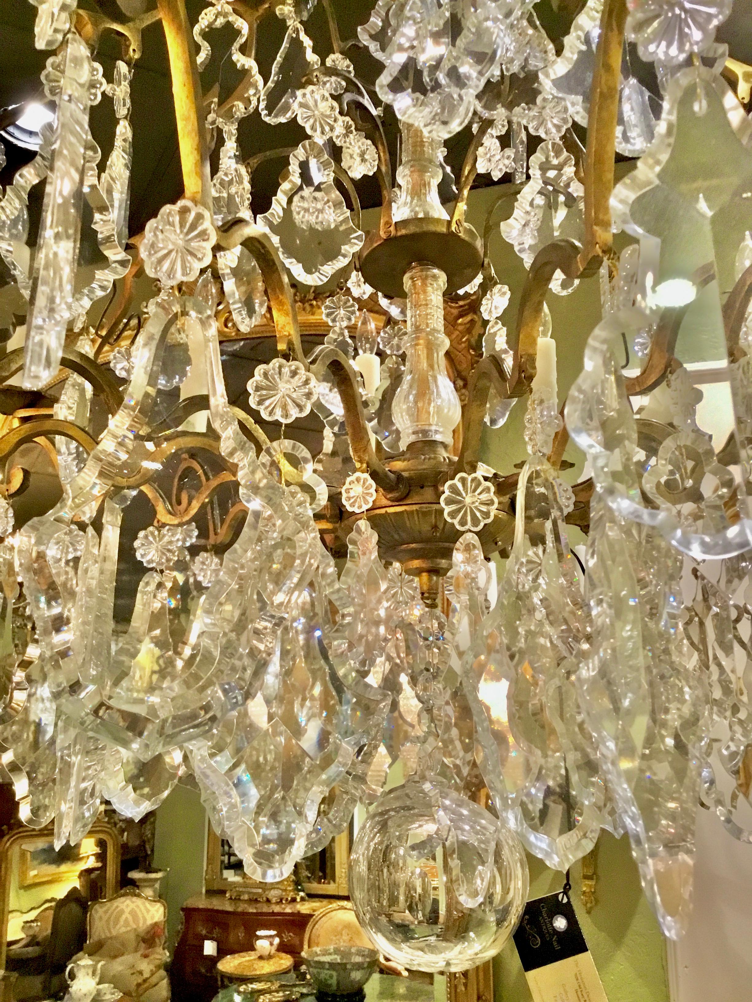 Exceptional crystal and bronze chandelier with 12-light around the perimeter with a central crystal stem.
Having scrolling arms and large crystal pendants. The tall fixture 
Has Crystal around the shaped glass central stem.
The gilt bronze has a