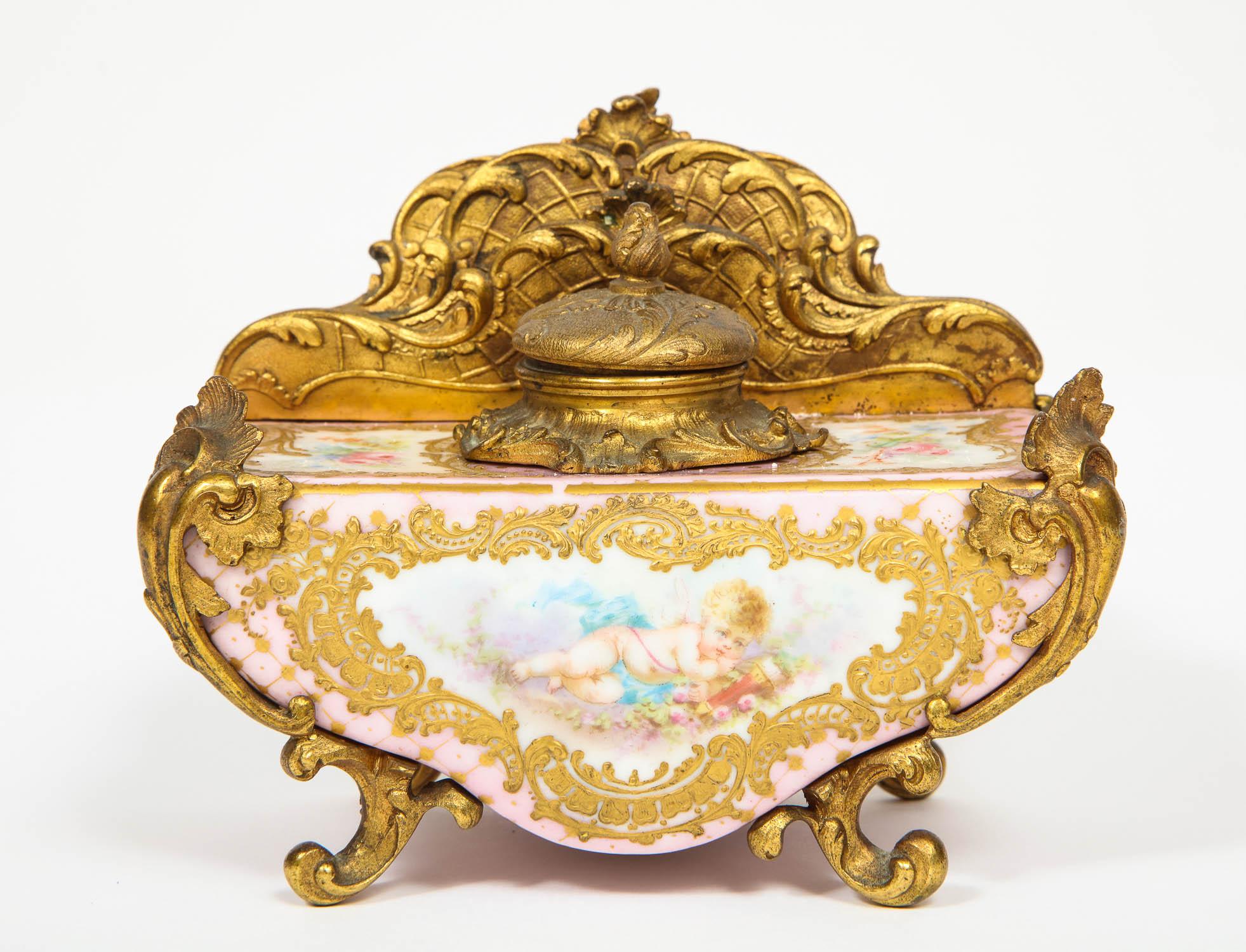 A French gilt bronze and pink Sèvres Porcelain inkwell and letter holder, 
circa 1880

With raised gold, hand-painted with putti and flowers.

Measures: 4.5
