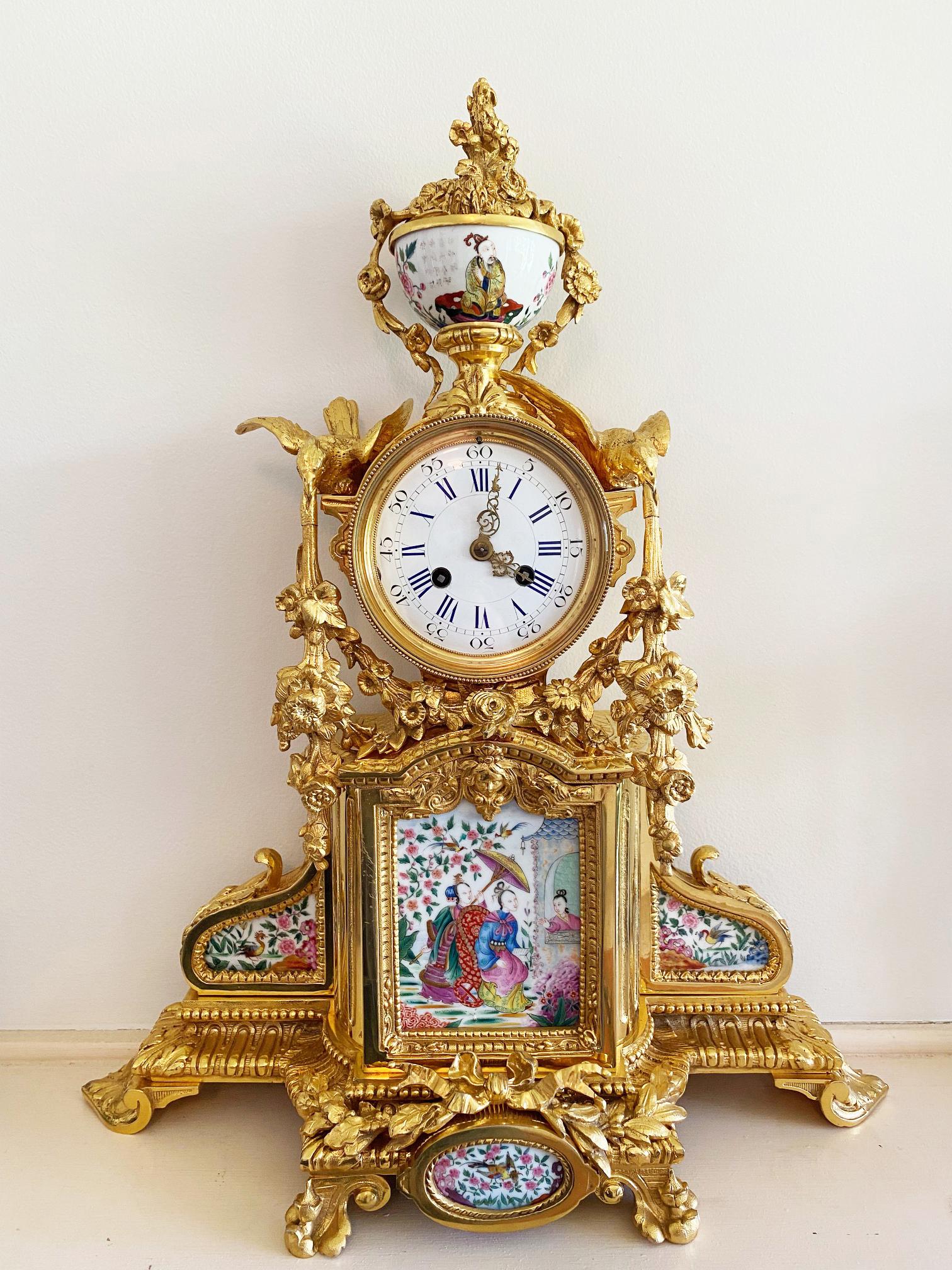 A very attractive French gilt bronze and ceramic mantel clock, profusely decorated with  floral swags, flowers, ribbons, birds and masks and surmounted by a ceramic and bronze baroque style urn swathed in fruit and flowers. The original gilding in