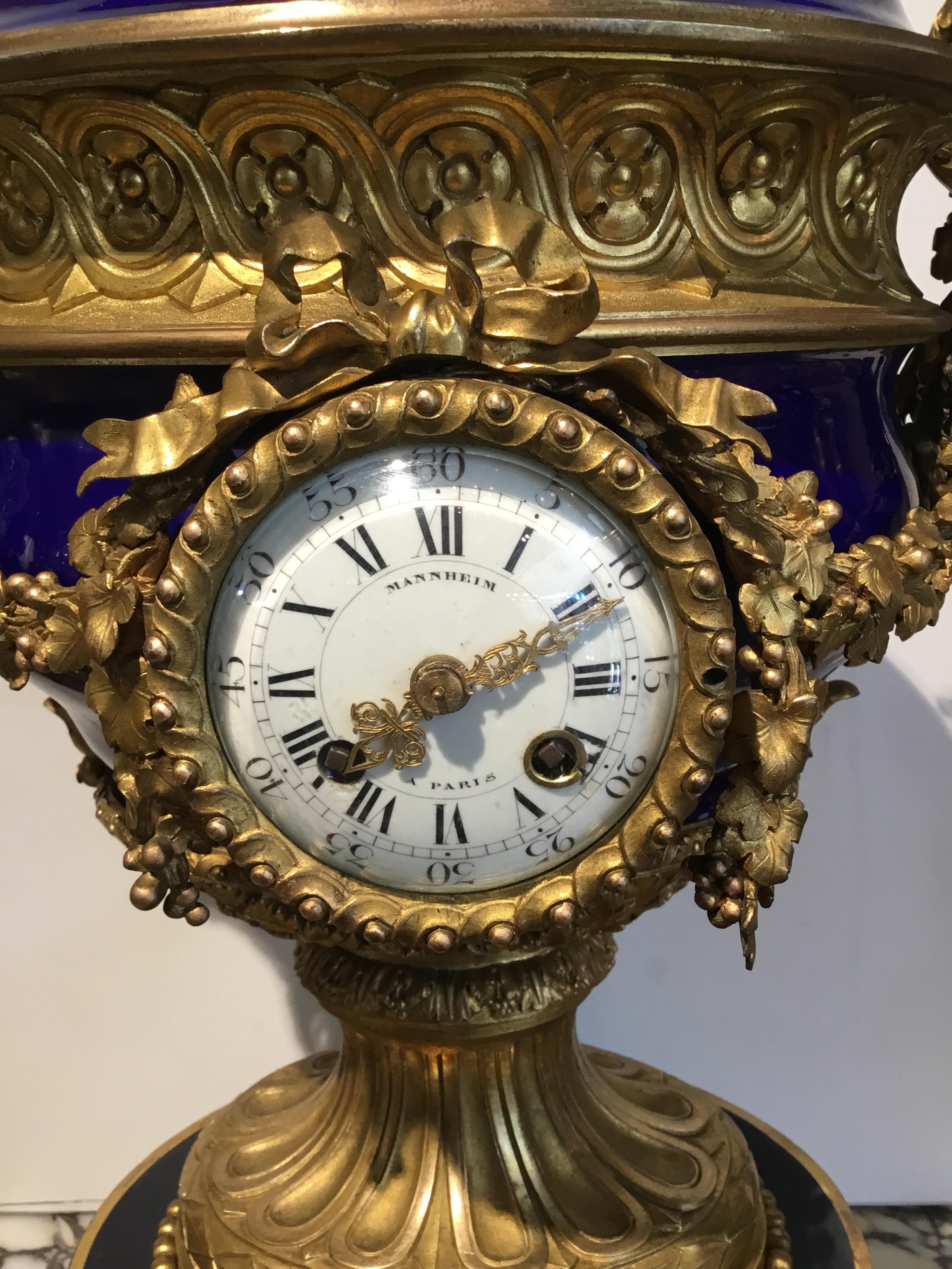 Large and exquisite urn form clock with cobalt porcelain and gilt bronze
Mounts. Signed on face Mannheim Paris. Pomegranate finial at the crest.
Scrolling arms to each side in grape leaf motif. Urn is resting on a circular
Base on gilt bronze.