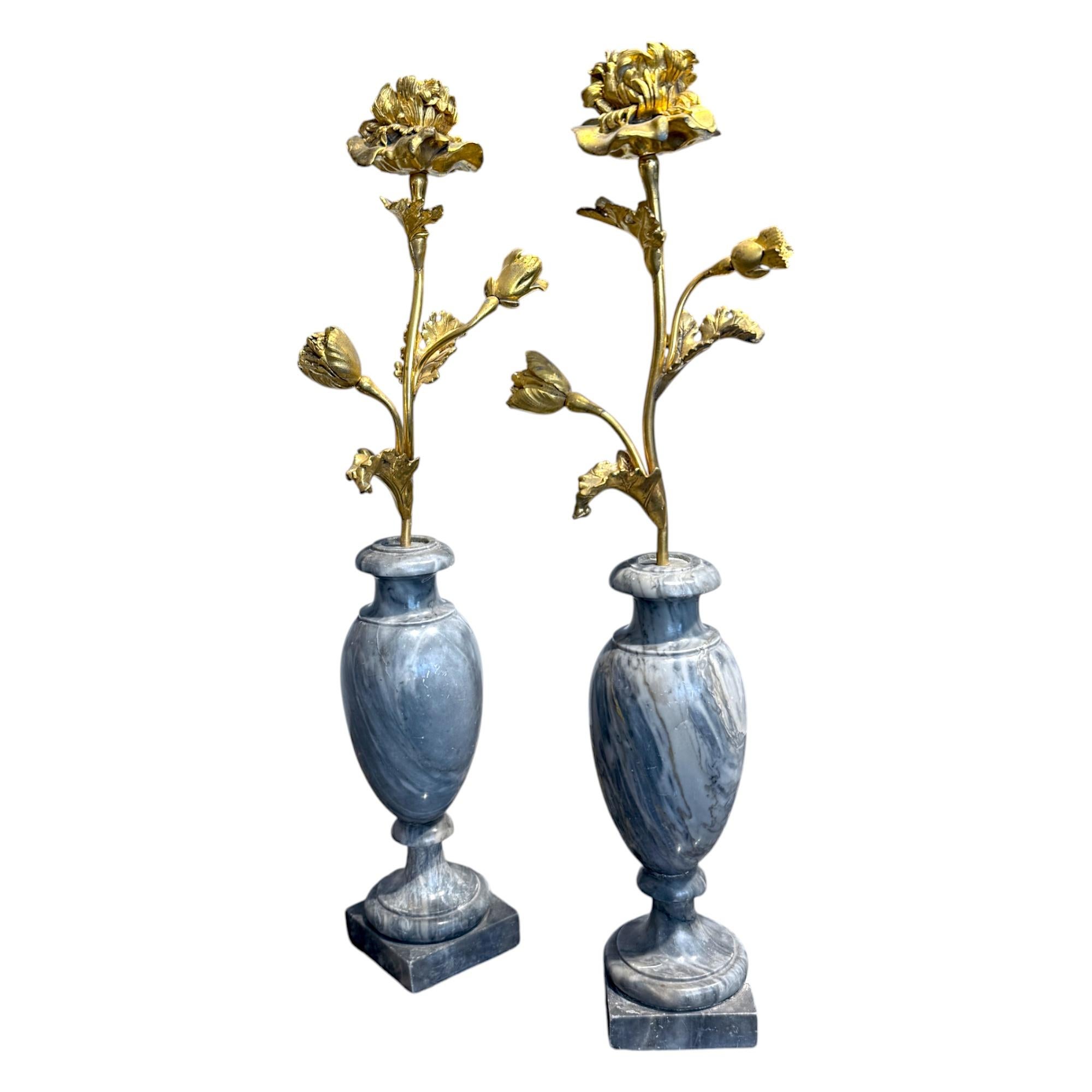 Coppia di candelieri francesi del XIX secolo, che combinano magistralmente materiali lussuosi con una raffinata eleganza neoclassica. Ogni candeliere presenta uno stelo floreale in bronzo dorato finemente fuso che si erge da un'elegante base a forma