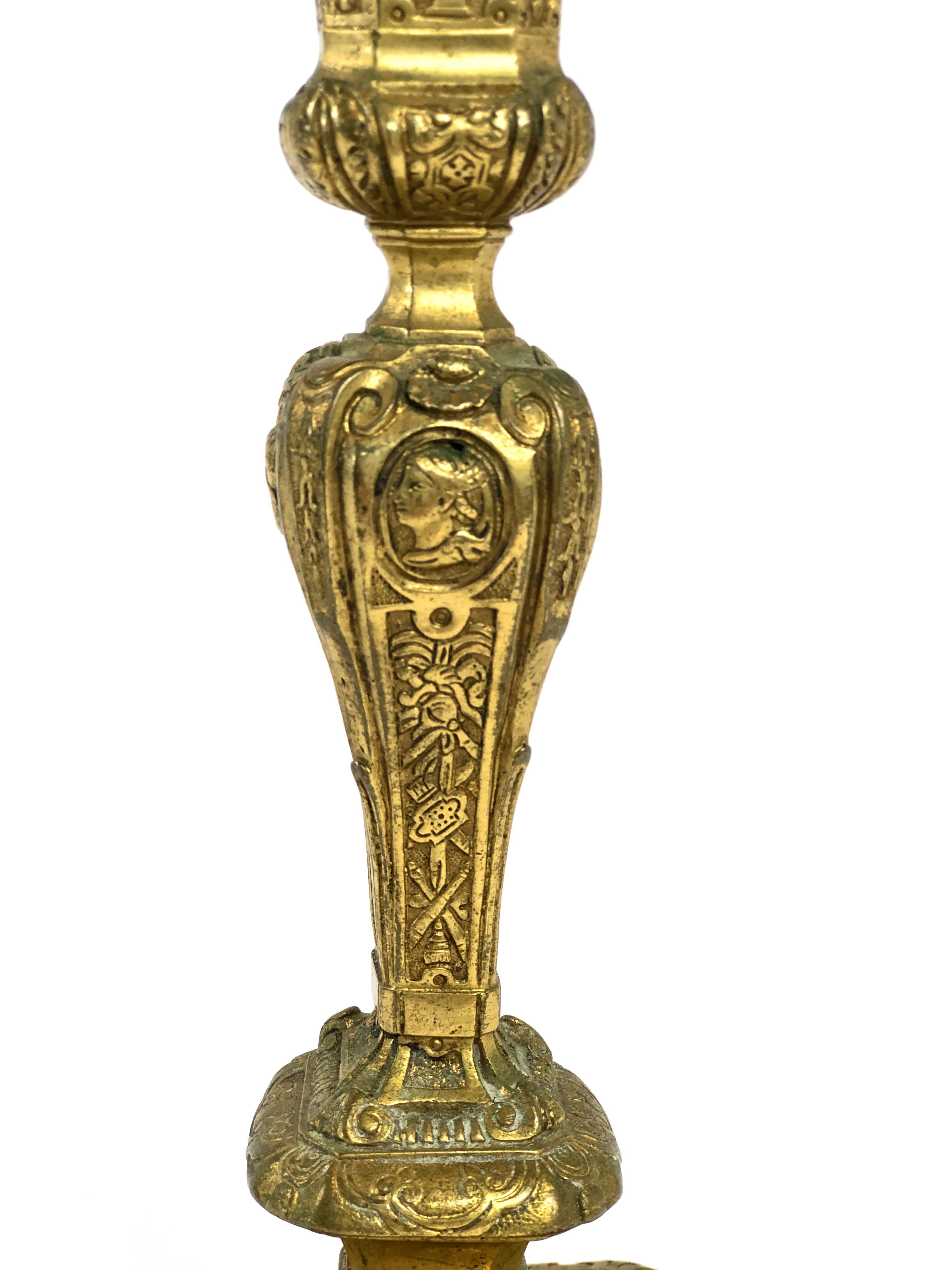Ein prächtiger Kerzenhalter im Stil Ludwigs XIV. aus dem 19. Jahrhundert, aus fein ziselierter und vergoldeter Bronze. Der balusterförmige Korpus ist reich verziert mit Schwaden und Wirbeln, Vasenmotiven, Fantasiewesen, Draperien und
