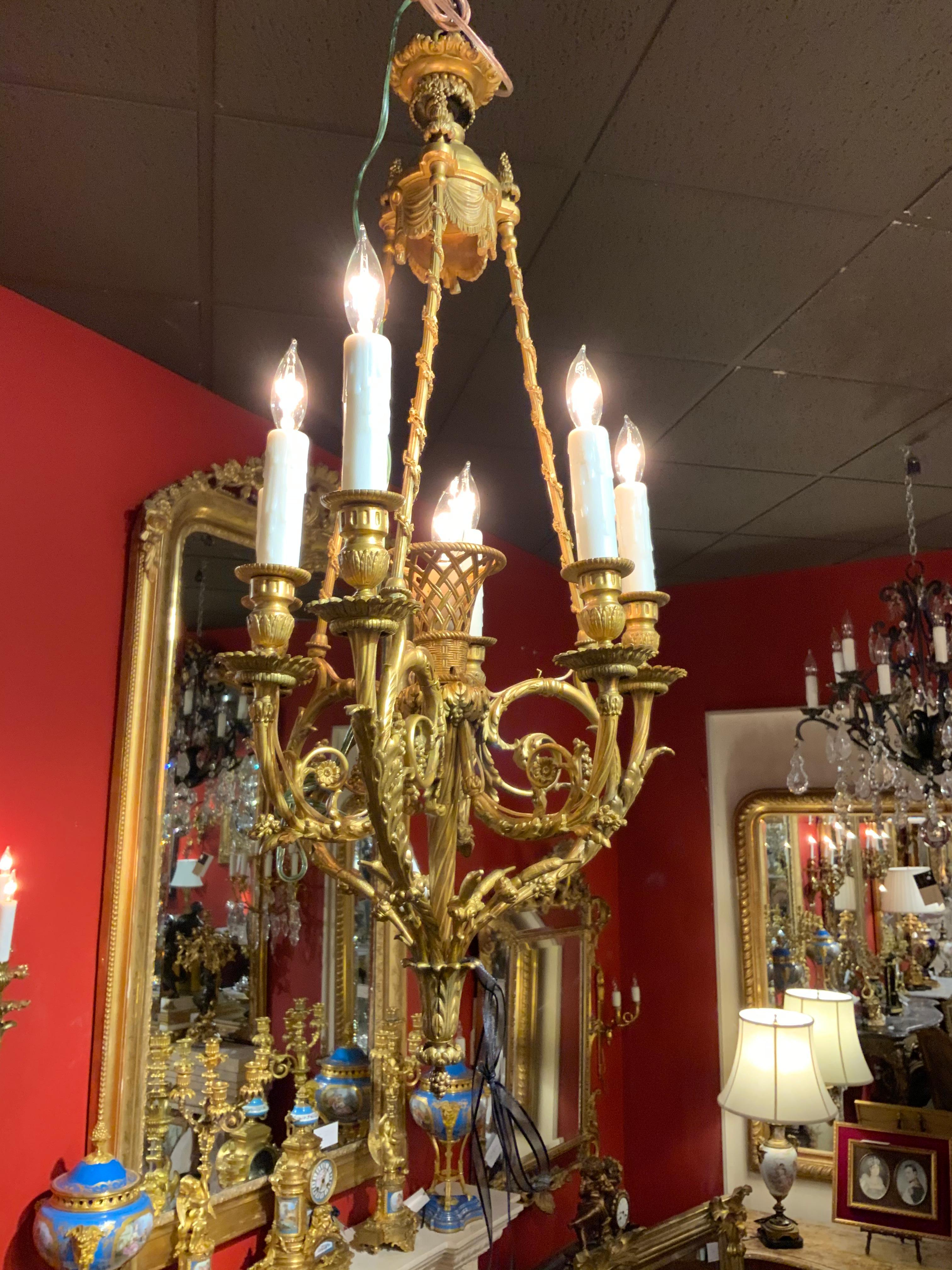Lovely French gilt bronze 7-light chandelier with a central basket that supports a light.
Six lights circle the perimeter being supported by ornate scrolling arms.