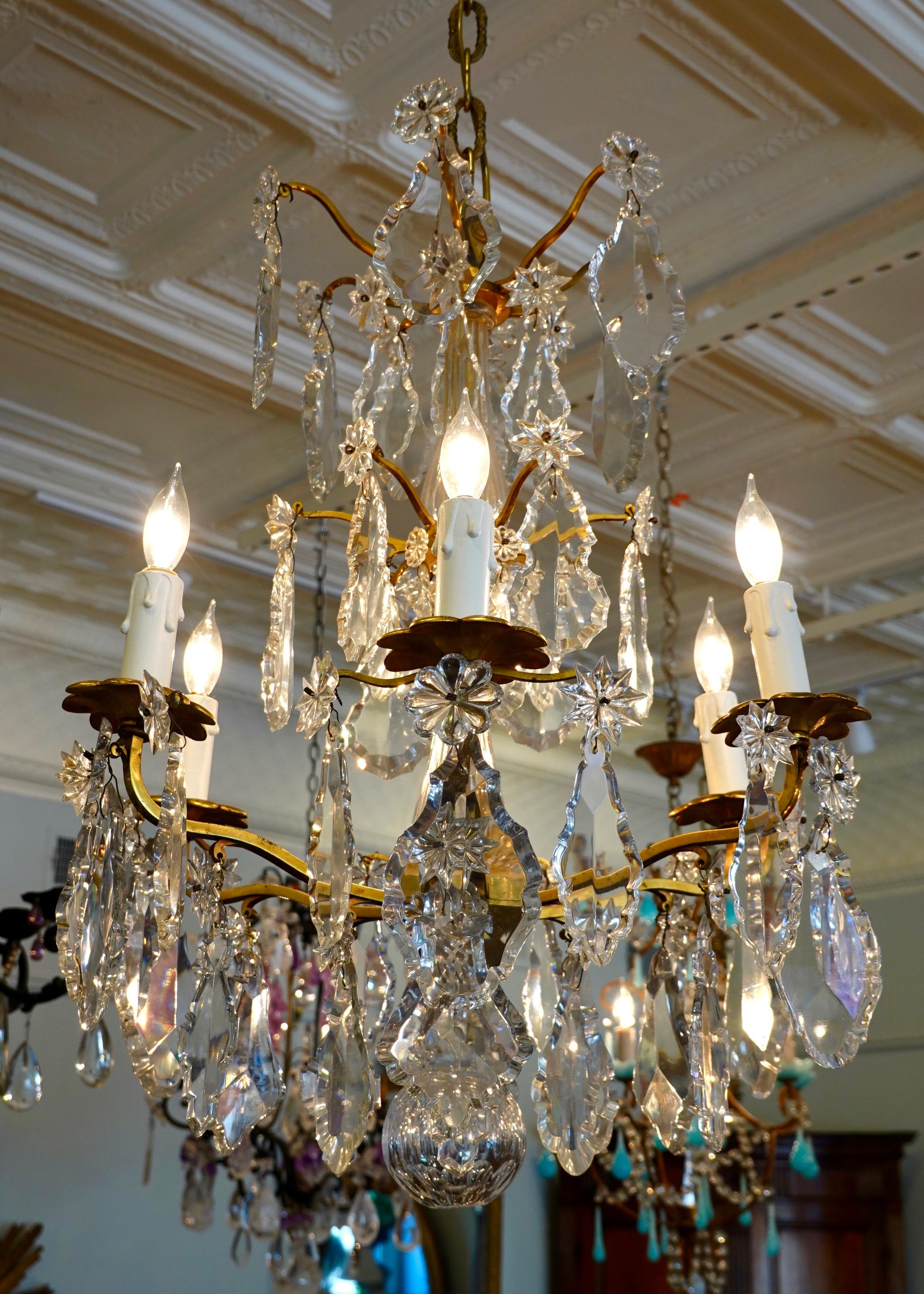 French Louis XV style gilt-bronze and crystal chandelier, electrified with six lights. This chandelier features exceptional, large cut crystal pendalogues, stars and rosettes, and a hollow cut crystal ball. The chandelier has been rewired for the US.