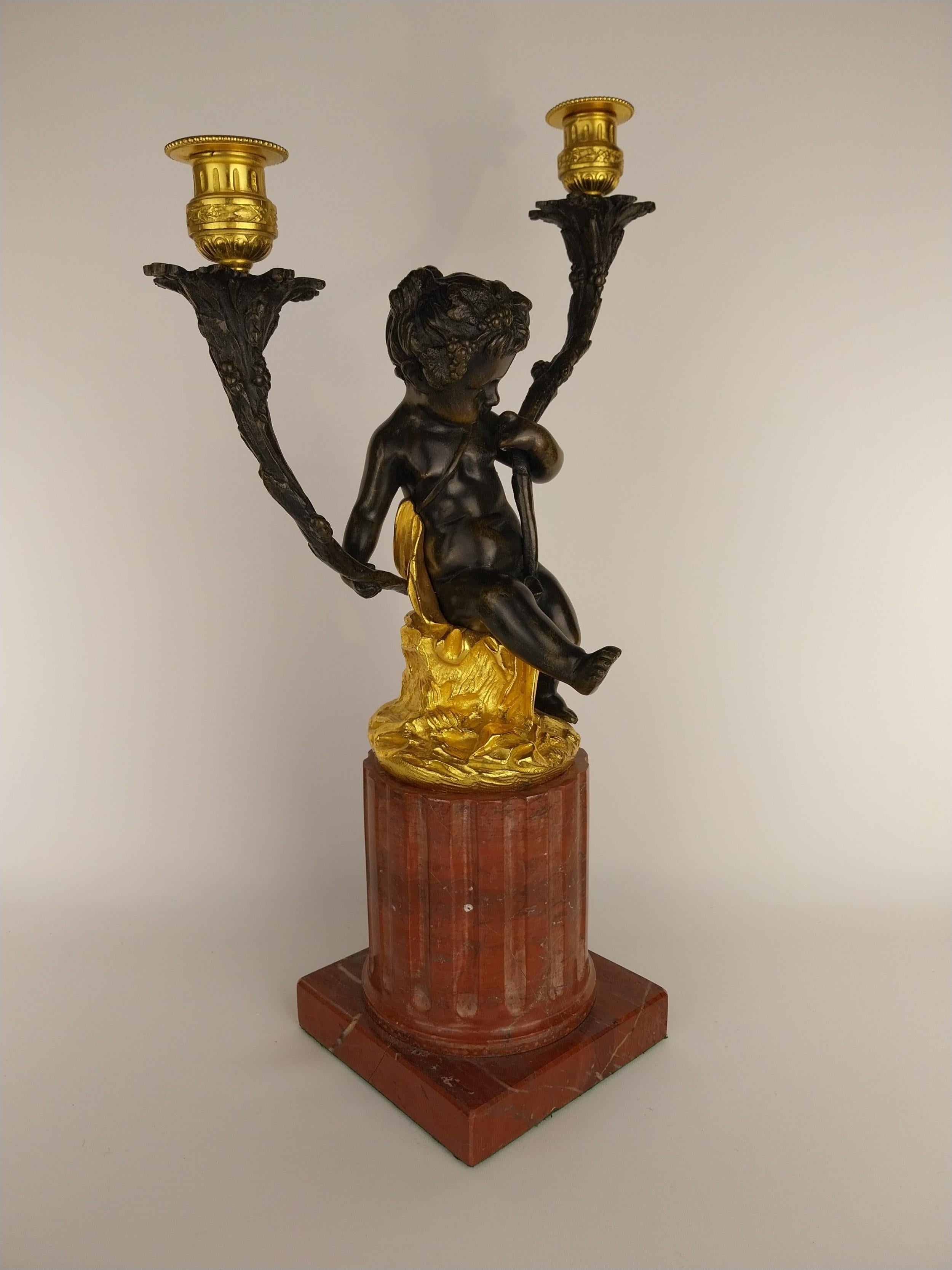 Gilt Bronze Candlestick cast in the form of a Cherub holding twin vine cast candle arms whilst sat on a gilt bronze tree stump and finished with fluted Rouge Marble base.
French Circa 1880
55cm tall x 25cm wide x 25cm deep