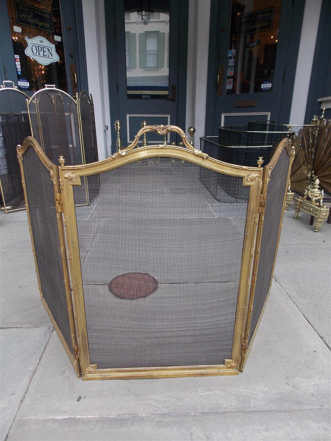 French gilt bronze arched three-panel folding fireplace screen with a scrolled centered floral and shell handle, reeded ribbon border, flanking urn finials, corner floral medallions, and decorative acanthus corners, Early 19th century
Each panel