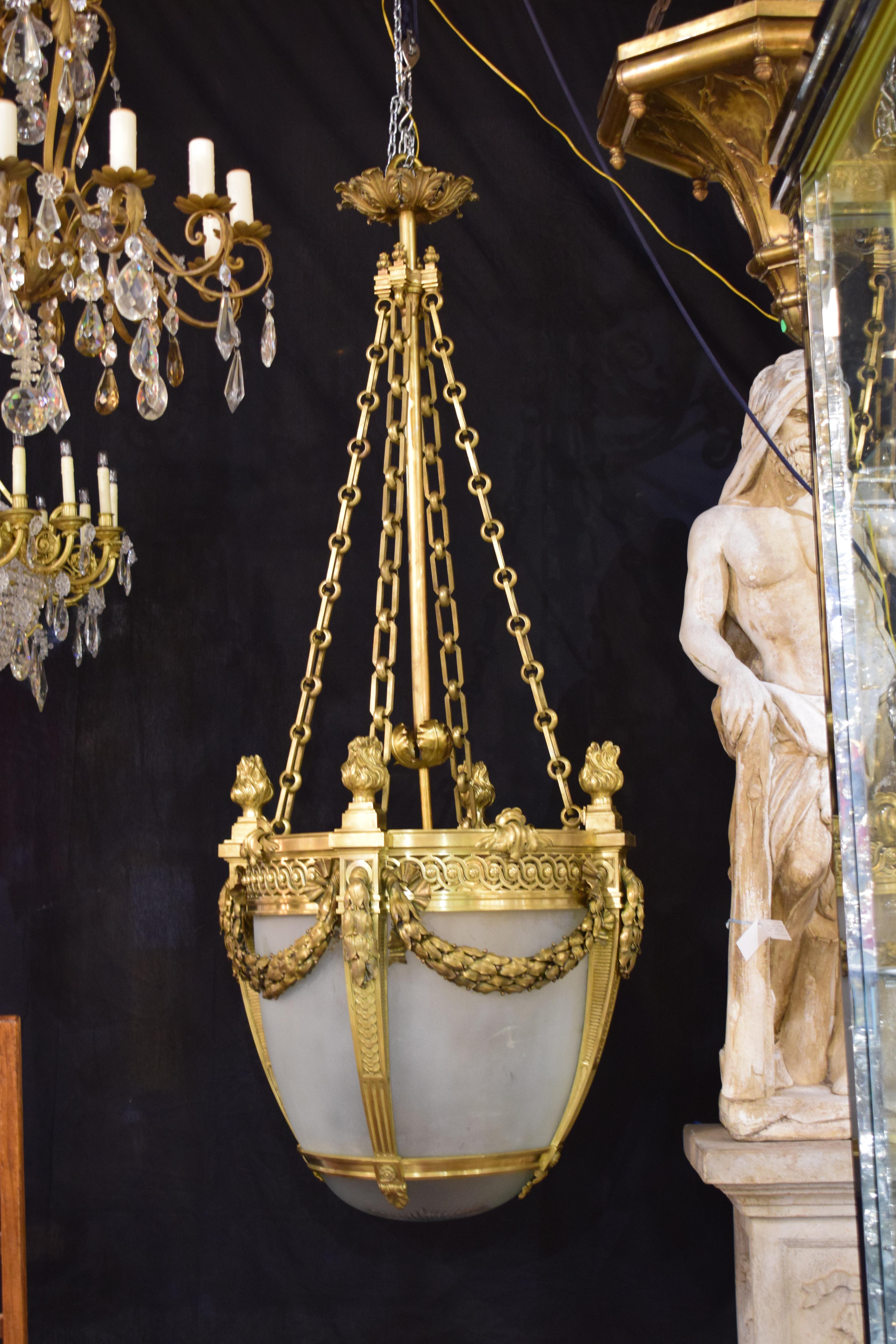 A very fine acorn shaped lantern. The top support issuing four chains that end on the main pierced gallery ornated with gilt bronze flames. The four main ribs separate the frosted glass panels. In between ribs repousse garlands and bows of the