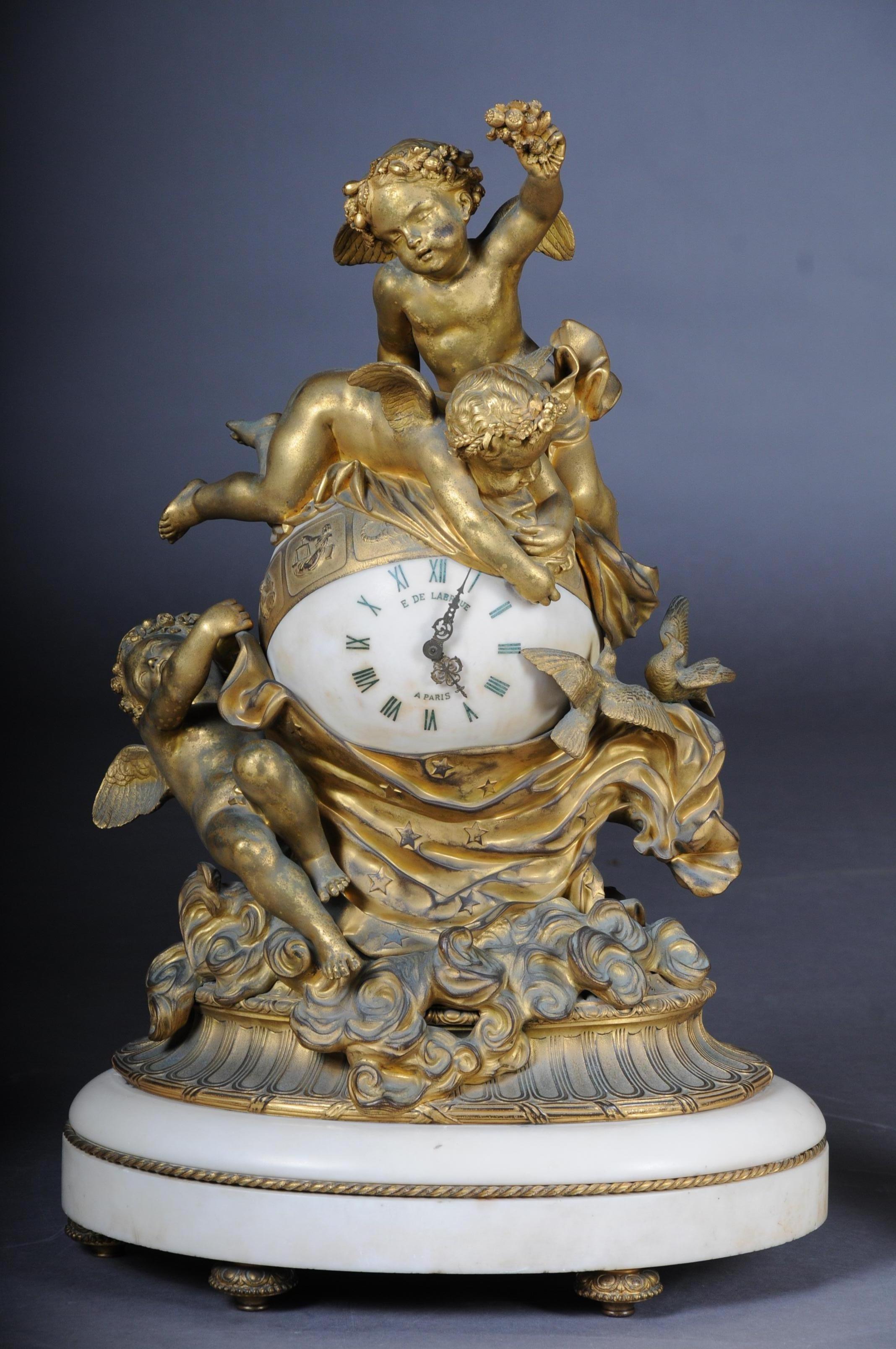 French gilt-bronze and carrara marble clock garniture by E.De. Labroue, Paris, circa 1890.

emblematic of the cloth of dusk being drawn over the earth, three putti and two doves raised on a cloudbank, the spherical clockcase signed E. DE. LABROUE.