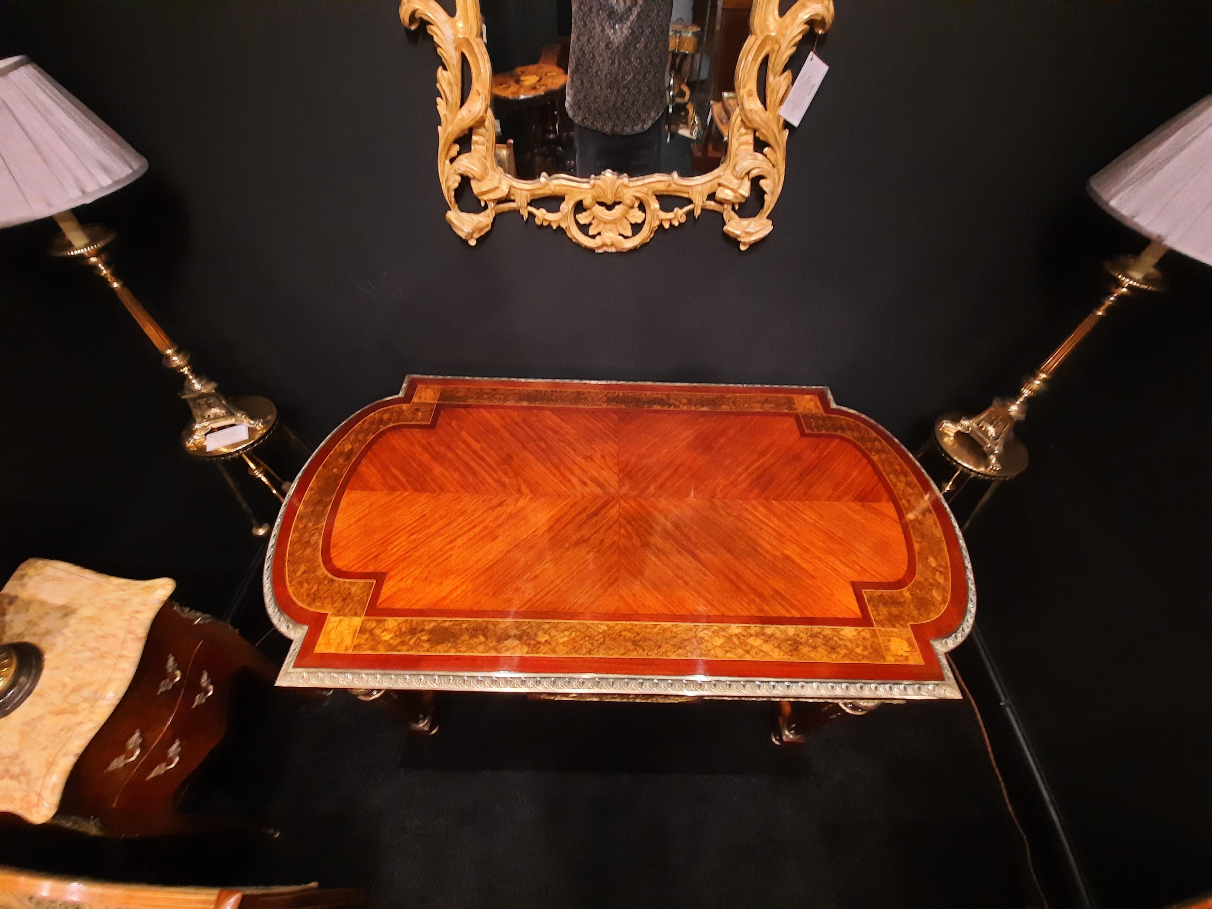 Table centrale en bois de roi, montée sur bronze doré, vers 1860, le plateau en quart de placage à bout arqué sur deux panneaux de frise moulés avec des scènes de Bacchanales, sur quatre pieds cannelés reliés par un X arqué centré par une urne dorée
