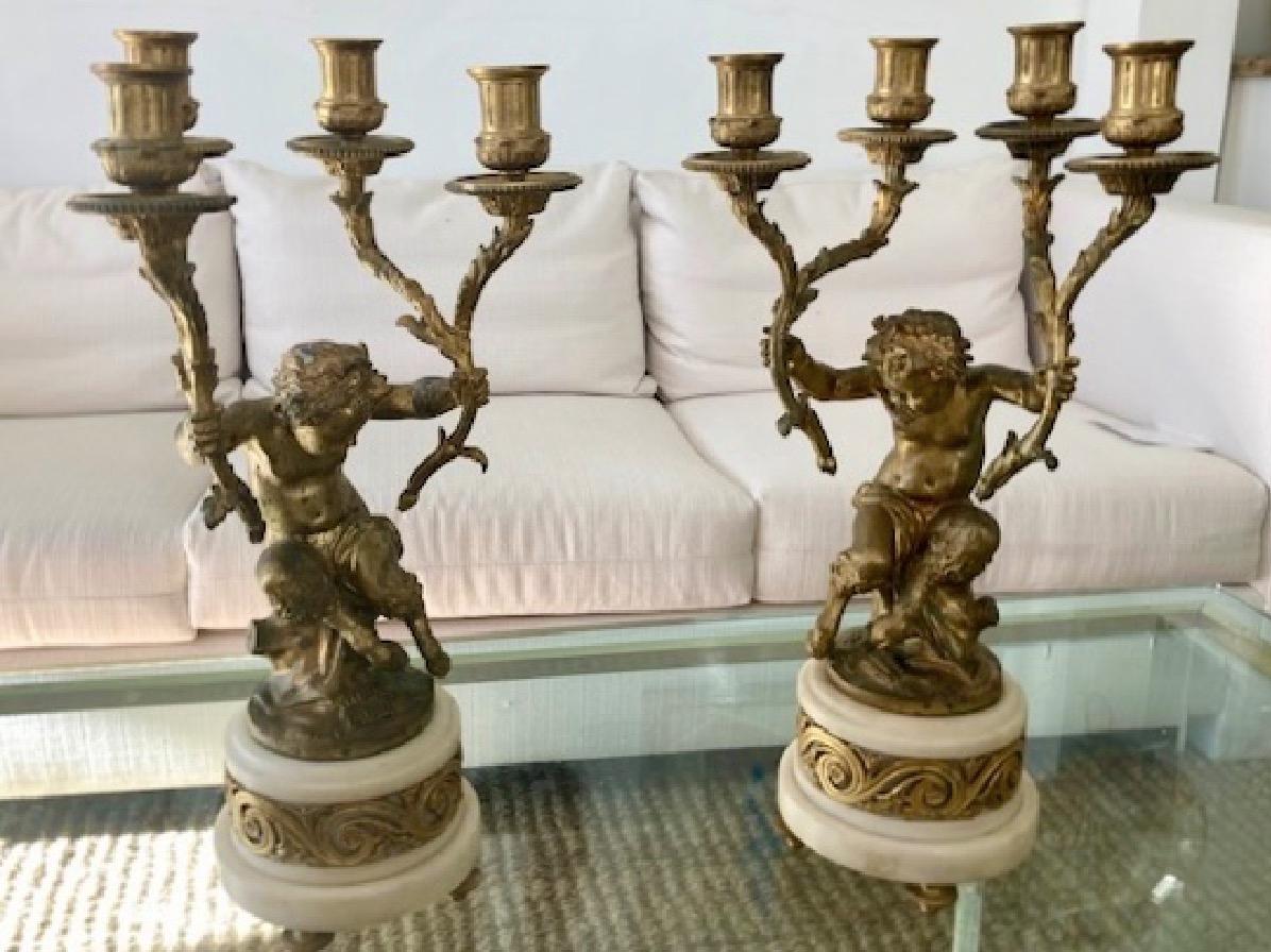 Belle paire de candélabres Pan Putti en bronze doré. Les détails de la sculpture sont remarquables.