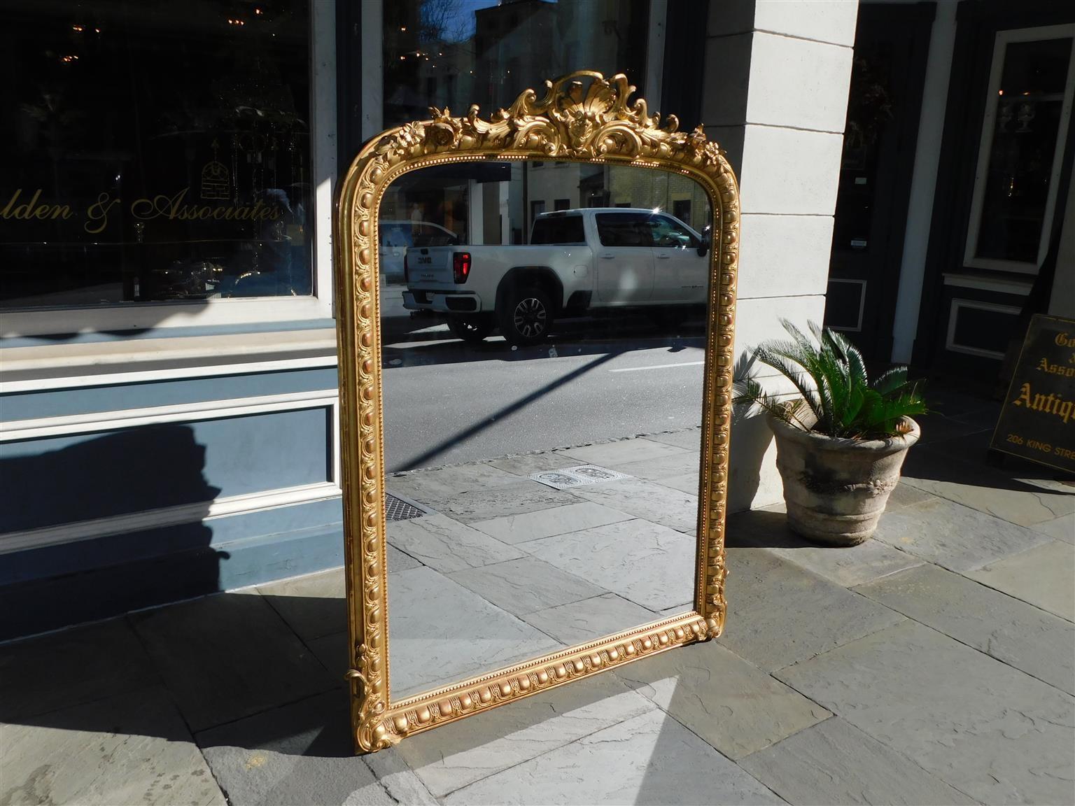 French gilt carved wood and gesso foliage cartouche wall mirror with an egg and dart exterior border, flanking acanthus carved corners, and interior bead work. Early 19th century. Mirror retains the original glass and wood backing.