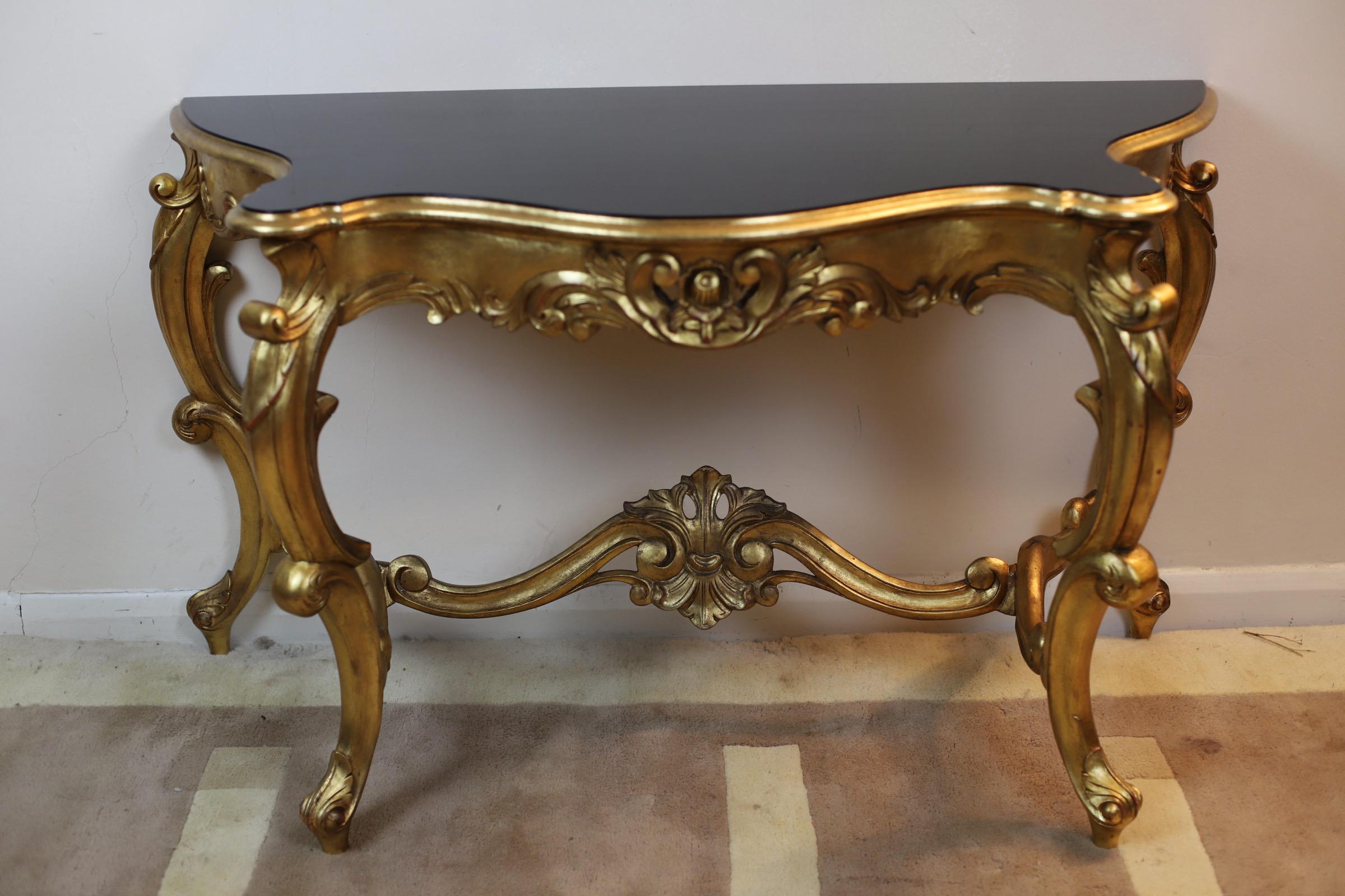 French Gilt Console Table - Louis XVI Carved Furniture.
Antique style gilt side table having ebonised top with decorated frieze, raised on C-scroll and cabriole supports with stretchers.

Don't hesitate to contact me if you have any