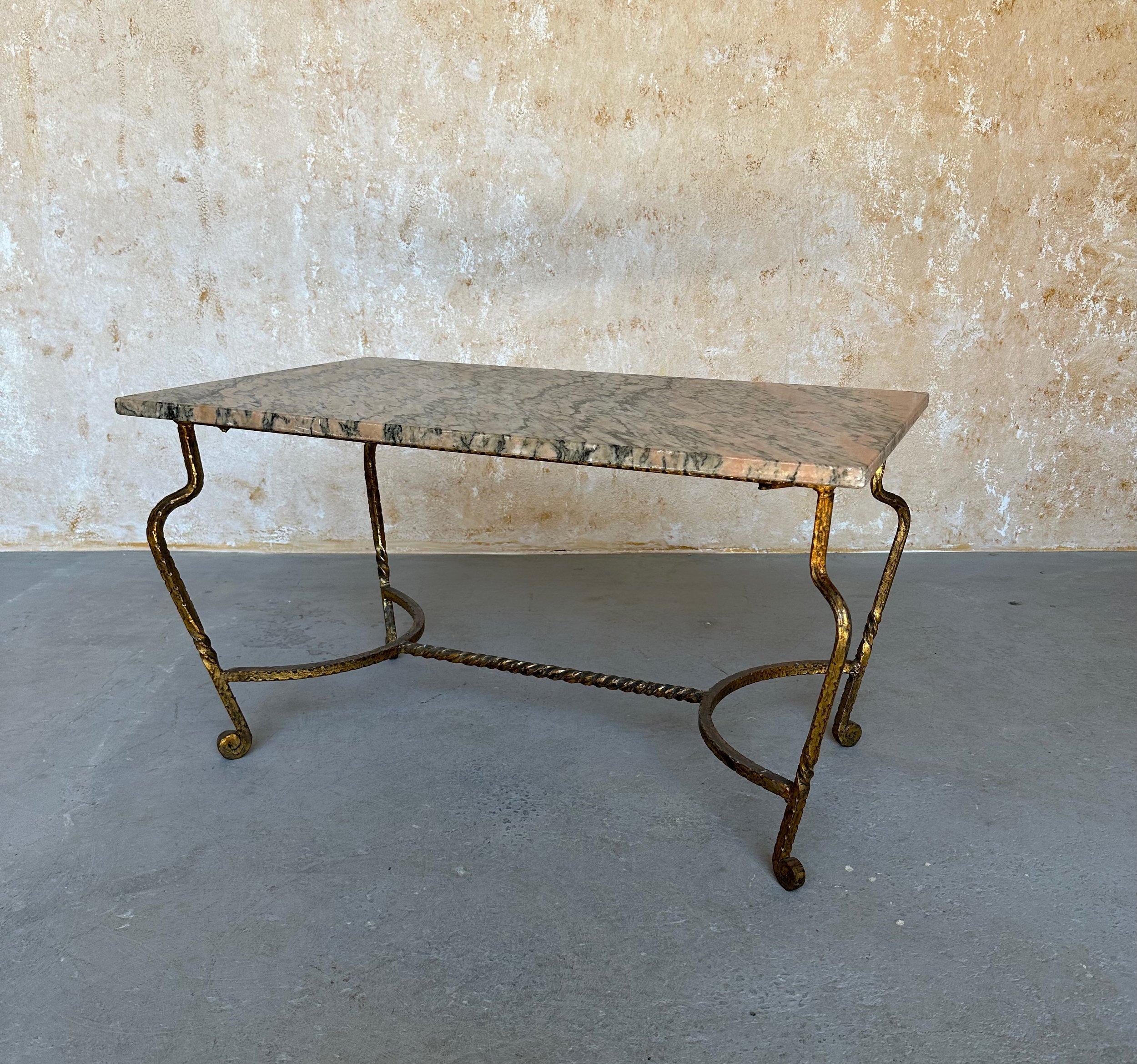 This elegant French 1950s coffee table features a unique twisted iron frame with hammered demi lune stretchers between the legs that support the central stretcher. The legs have extended curves and gently scrolled feet. The frame is finished in