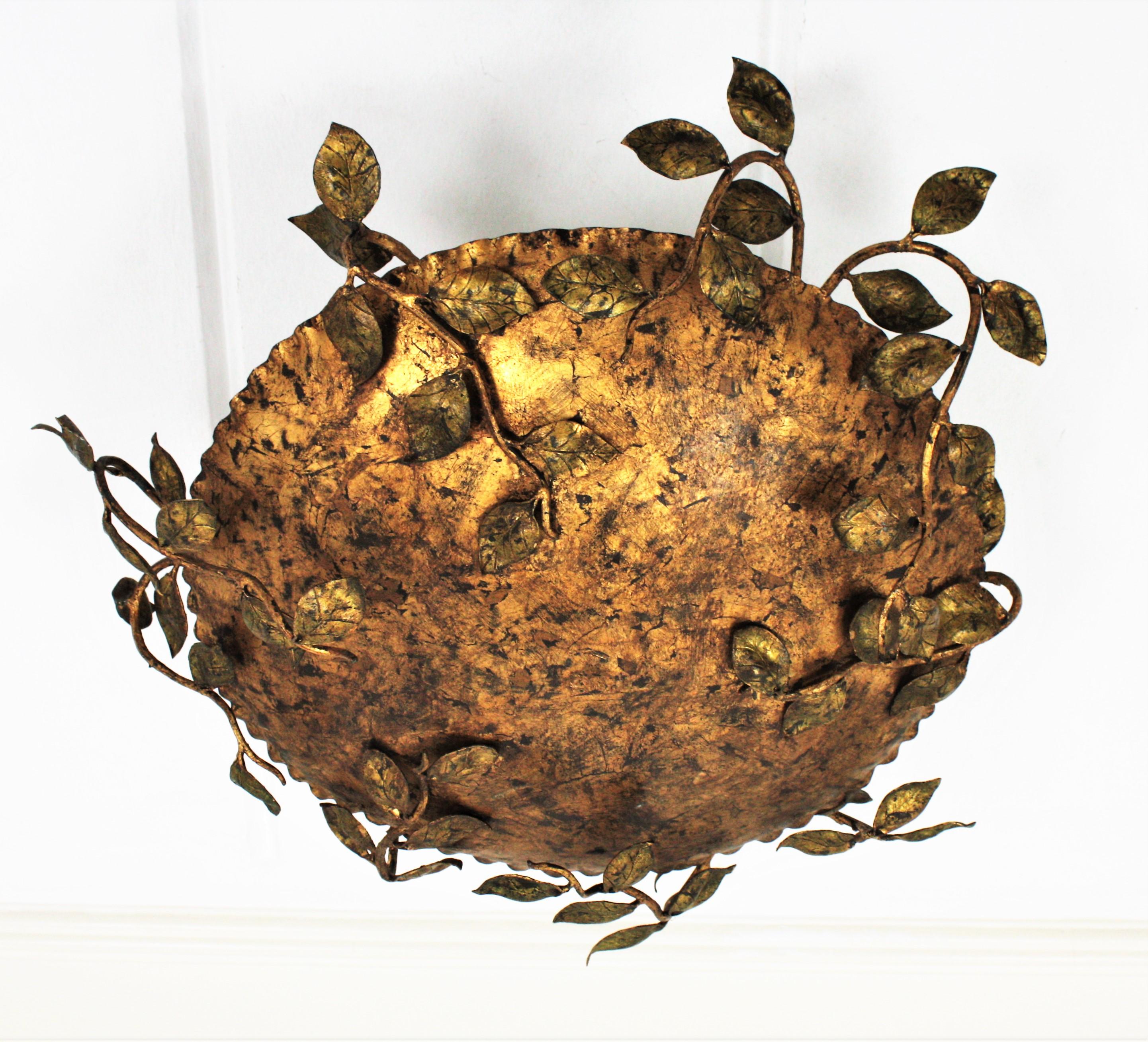 Rare gilt wrought iron flush mount or chandelier ornamented with branches and leaves. France, 1940s.
This gorgeous ceiling light fixture features a round flush mounted structure surrounded by an intricate of branches with small leaves with green