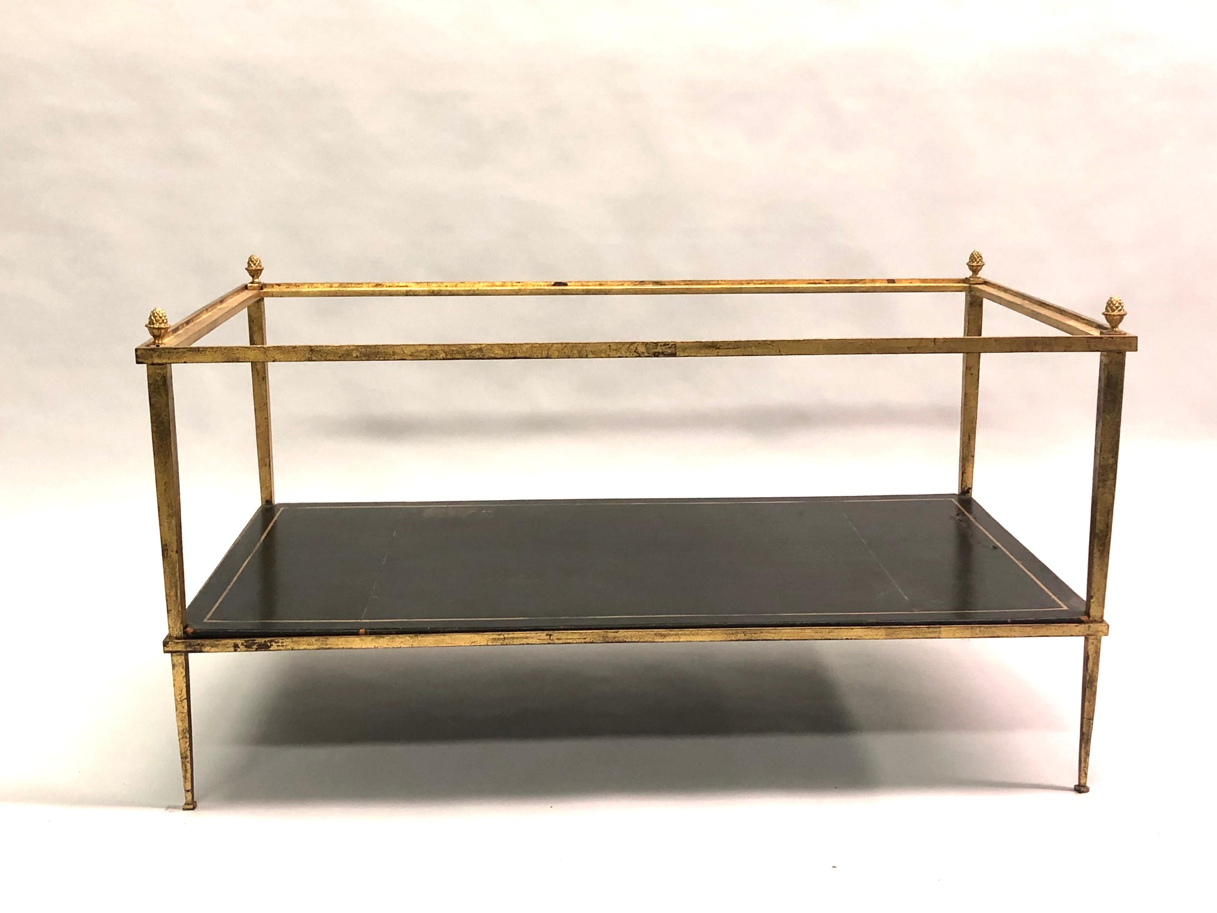 Table basse néoclassique moderne à double niveau, fabriquée par la Maison Ramsay pour la Maison Jansen, en fer doré, aux lignes délicates et aux pieds fuselés. La table est dotée d'un niveau inférieur en cuir gaufré or, d'un niveau supérieur en