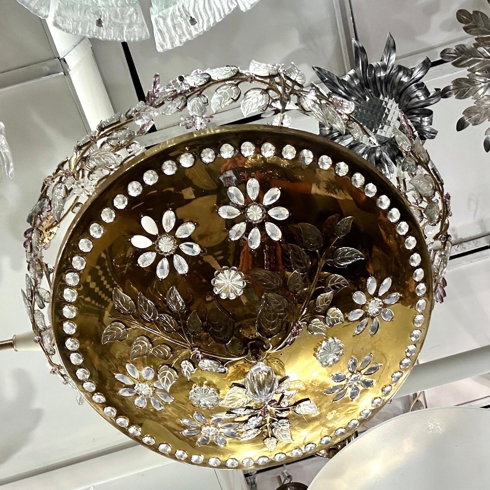 A circa 1950’s French gilt metal chandelier with crystal insets, molded glass leaves, cut amethyst crystal flowers and interior lights.

Measurements:
Diameter: 24″
Drop: 28″