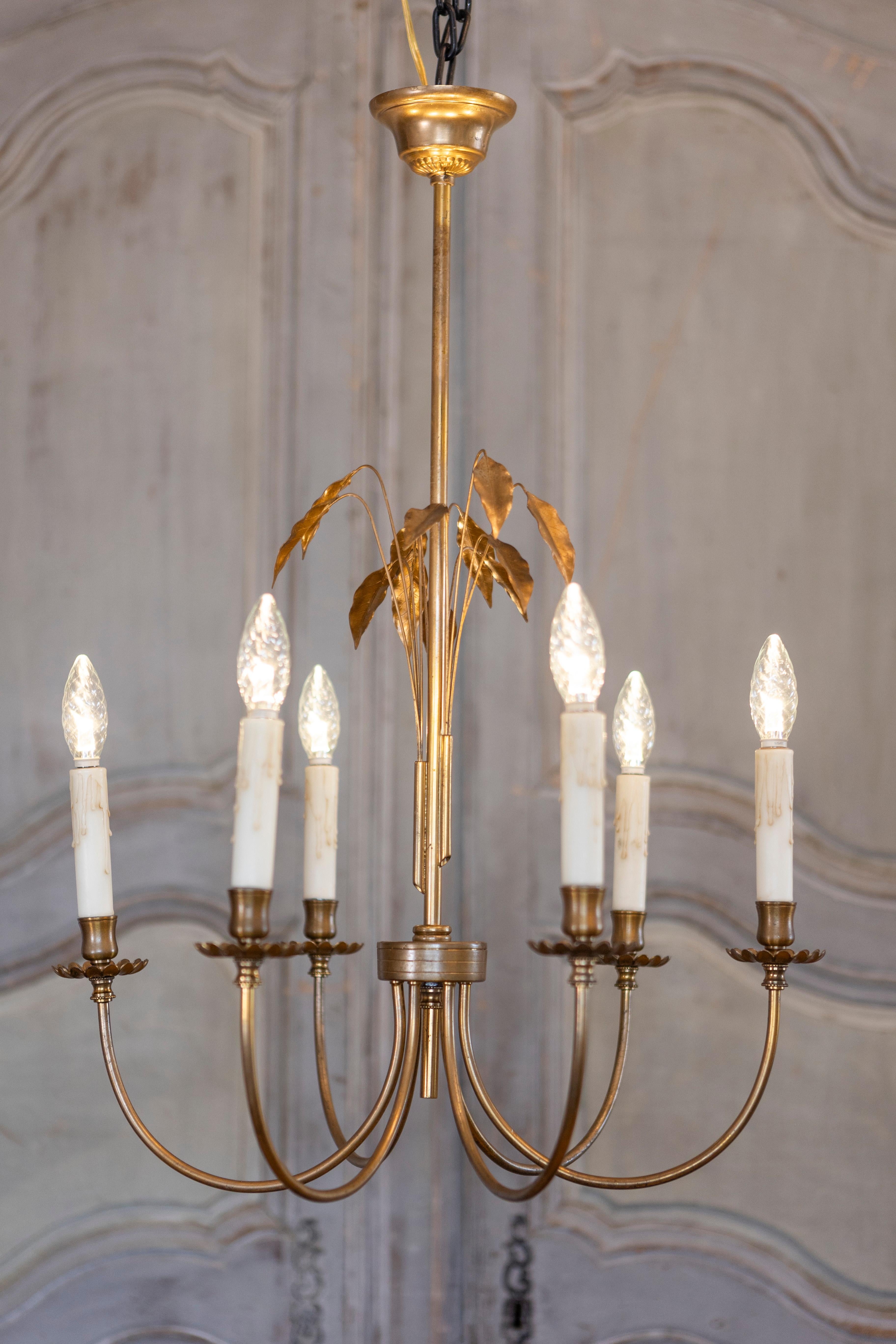 A French gilt metal six-light chandelier from the 20th century inspired by Maison Charles, with swoop arms and foliage motifs. This exquisite French gilt metal six-light chandelier from the 20th century, inspired by the renowned Maison Charles, is a