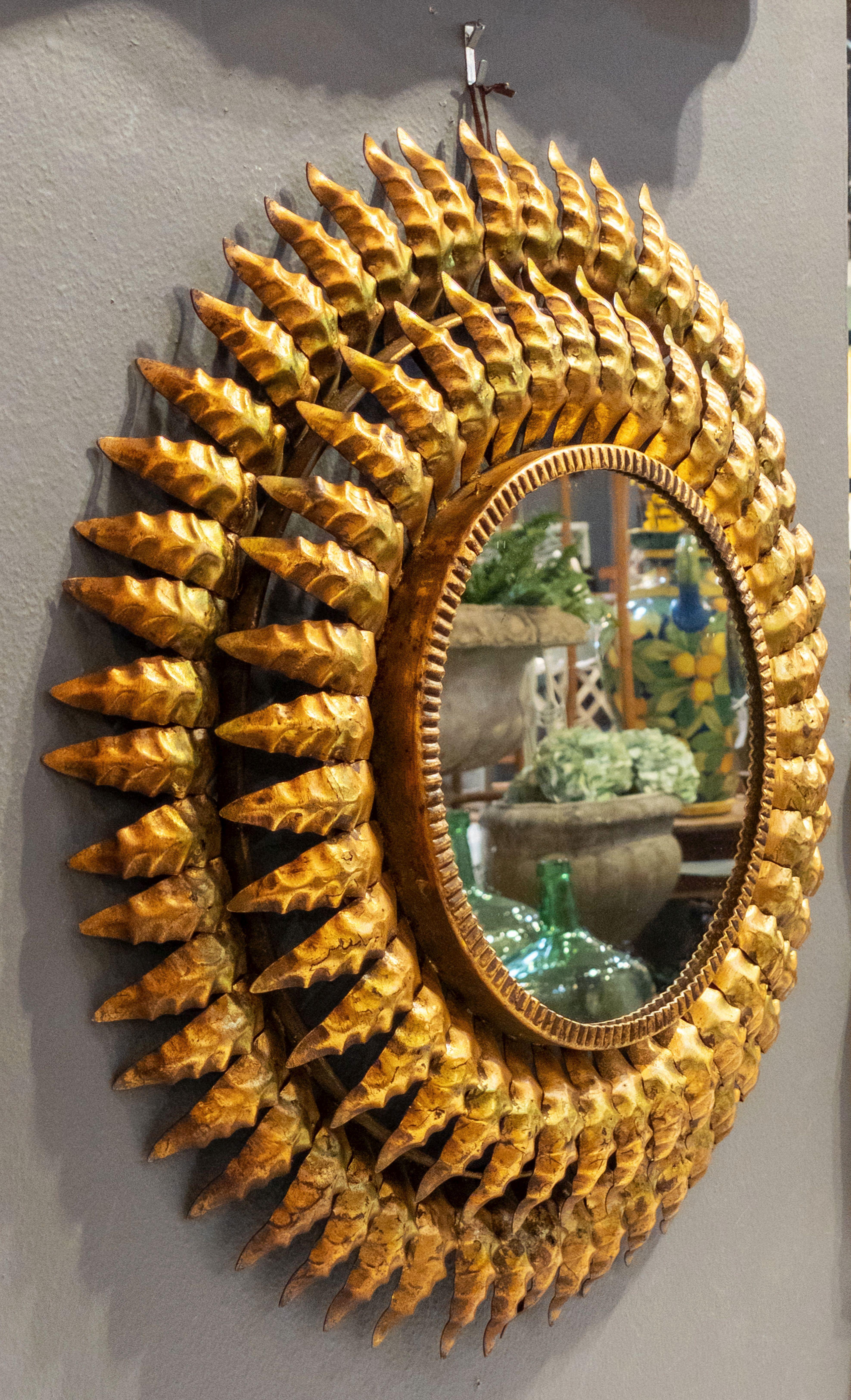 A lovely French sunburst (or starburst) mirror of gilt metal, 20 inches diameter, with round mirrored glass center in moulded frame.