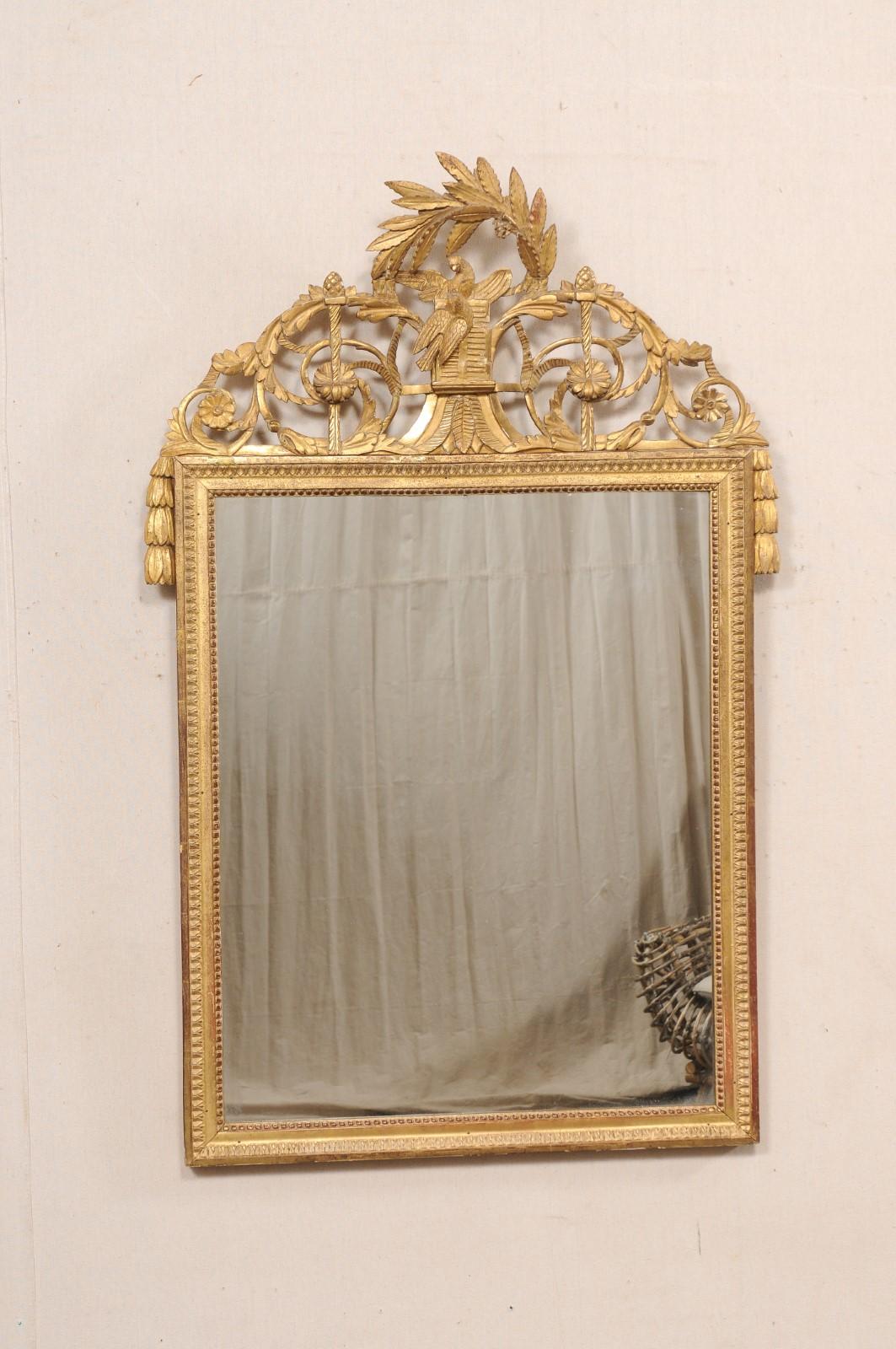 Specchio francese con cresta intagliata a traforo e legno dorato del XIX secolo. Questo specchio antico proveniente dalla Francia ha una forma rettangolare in vetro ornata da uno stemma in rilievo con colomba al centro, sotto un ramo di foglie ad