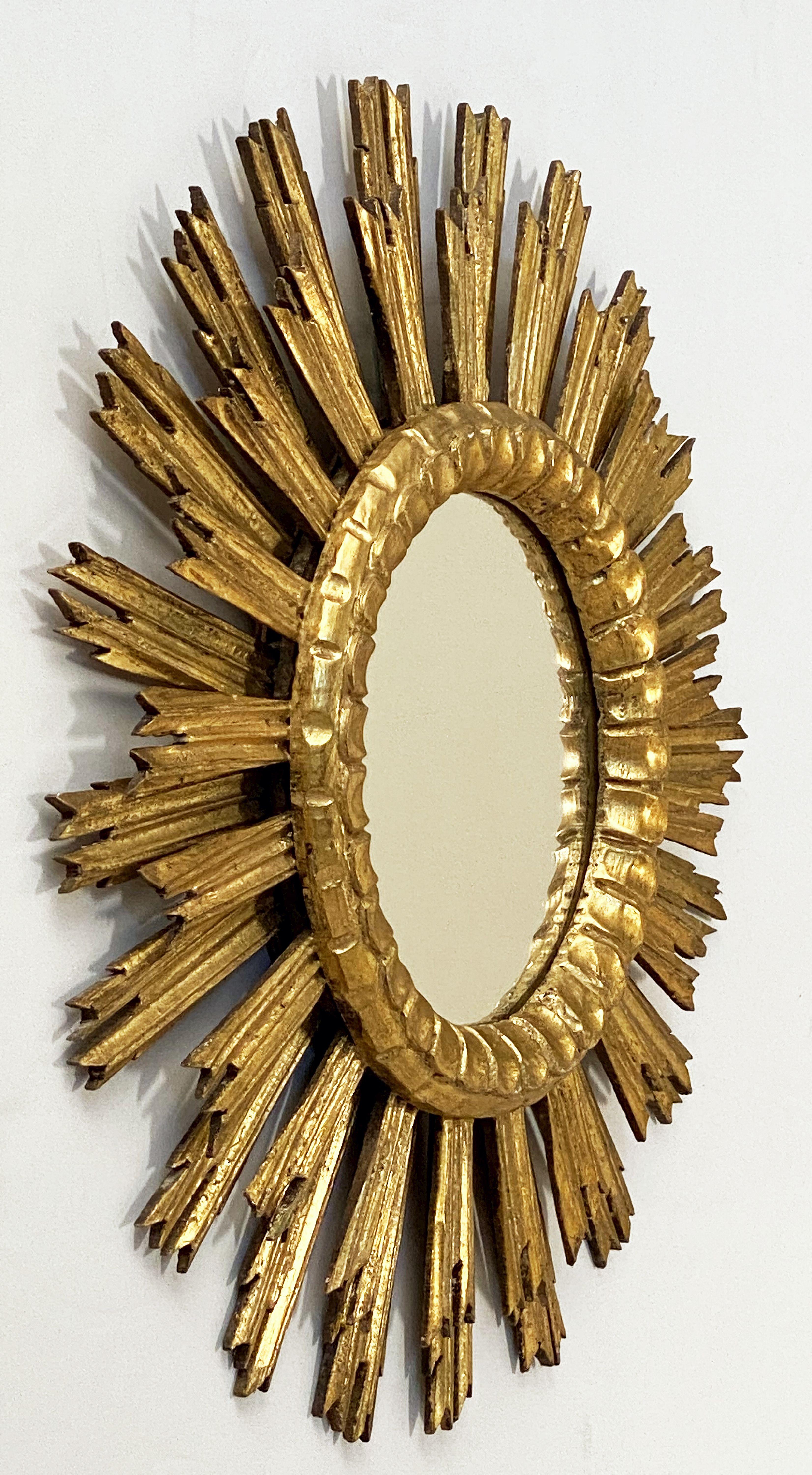 A lovely French gilt sunburst (or starburst) mirror, 24 inches diameter, with a round mirrored glass center in moulded frame.