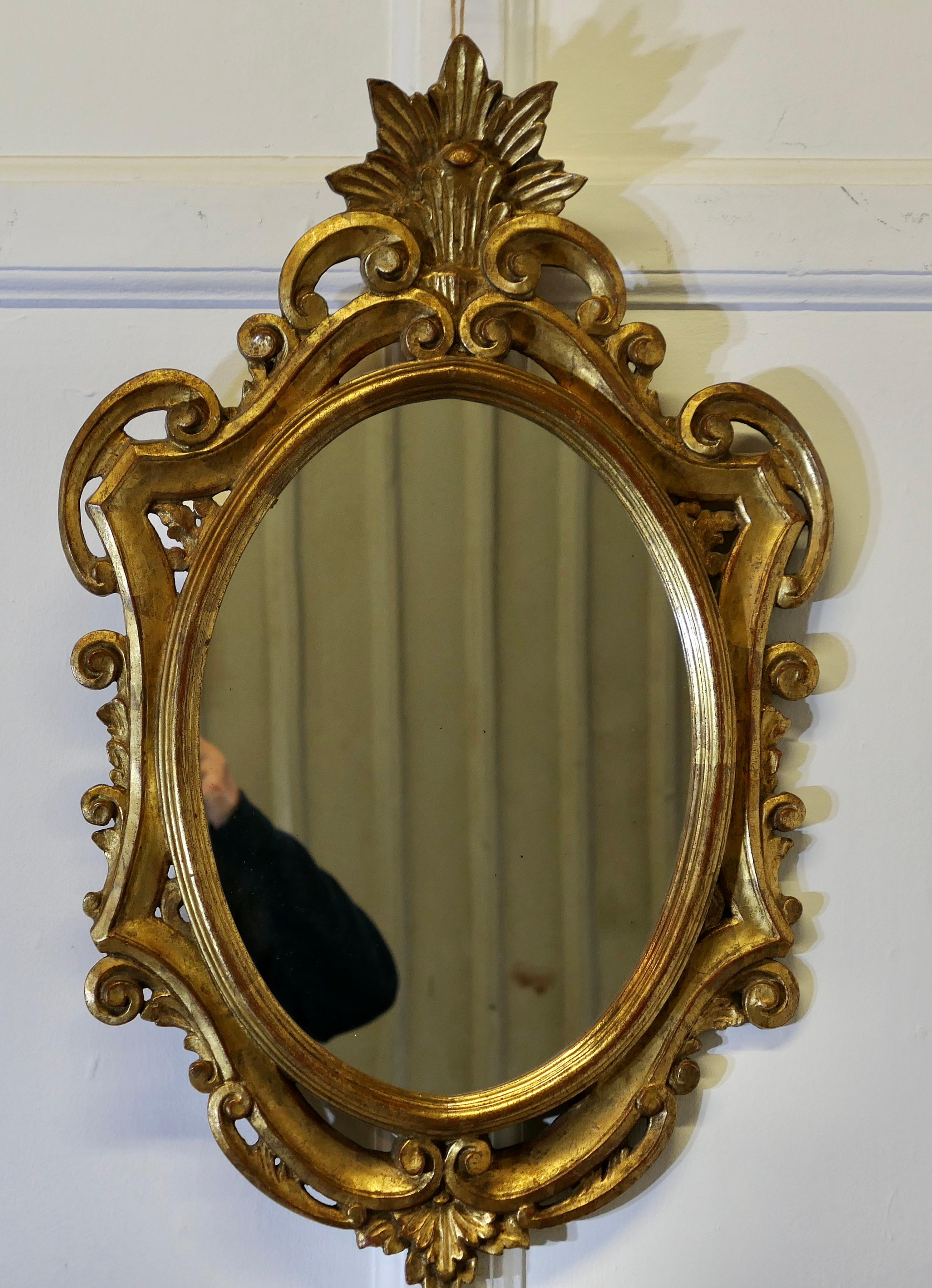 Specchio da parete francese dorato 

Questo specchio con cornice in gesso dorato ha una forma ovale al centro con fori e volute dorate, la finitura dorata è leggermente usurata e mostra il fondo rosso, ma è in buone condizioni. 
Lo specchio è alto
