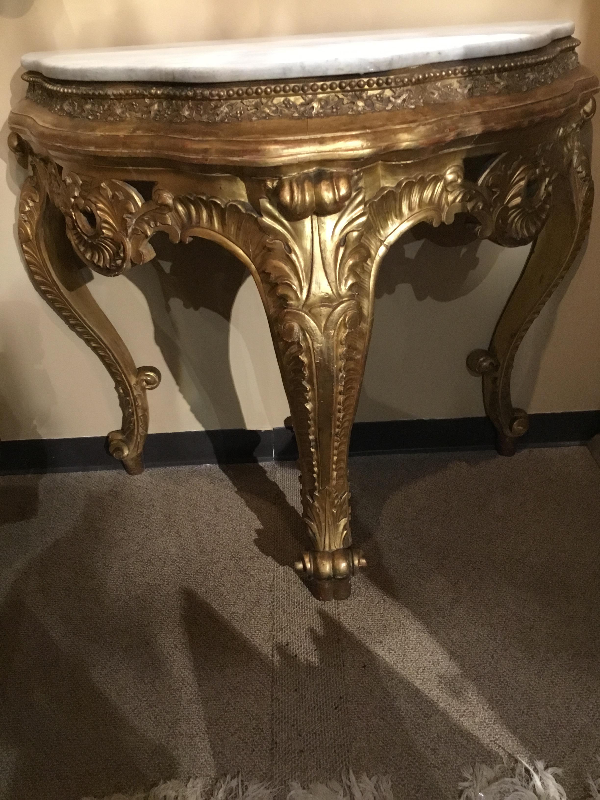 Giltwood neoclassical console table with bold curved leg with a whorl
Foot. A foliate carving surrounds the apron and a swirl design embellishes
The elegant curved legs. It is of demilune form.