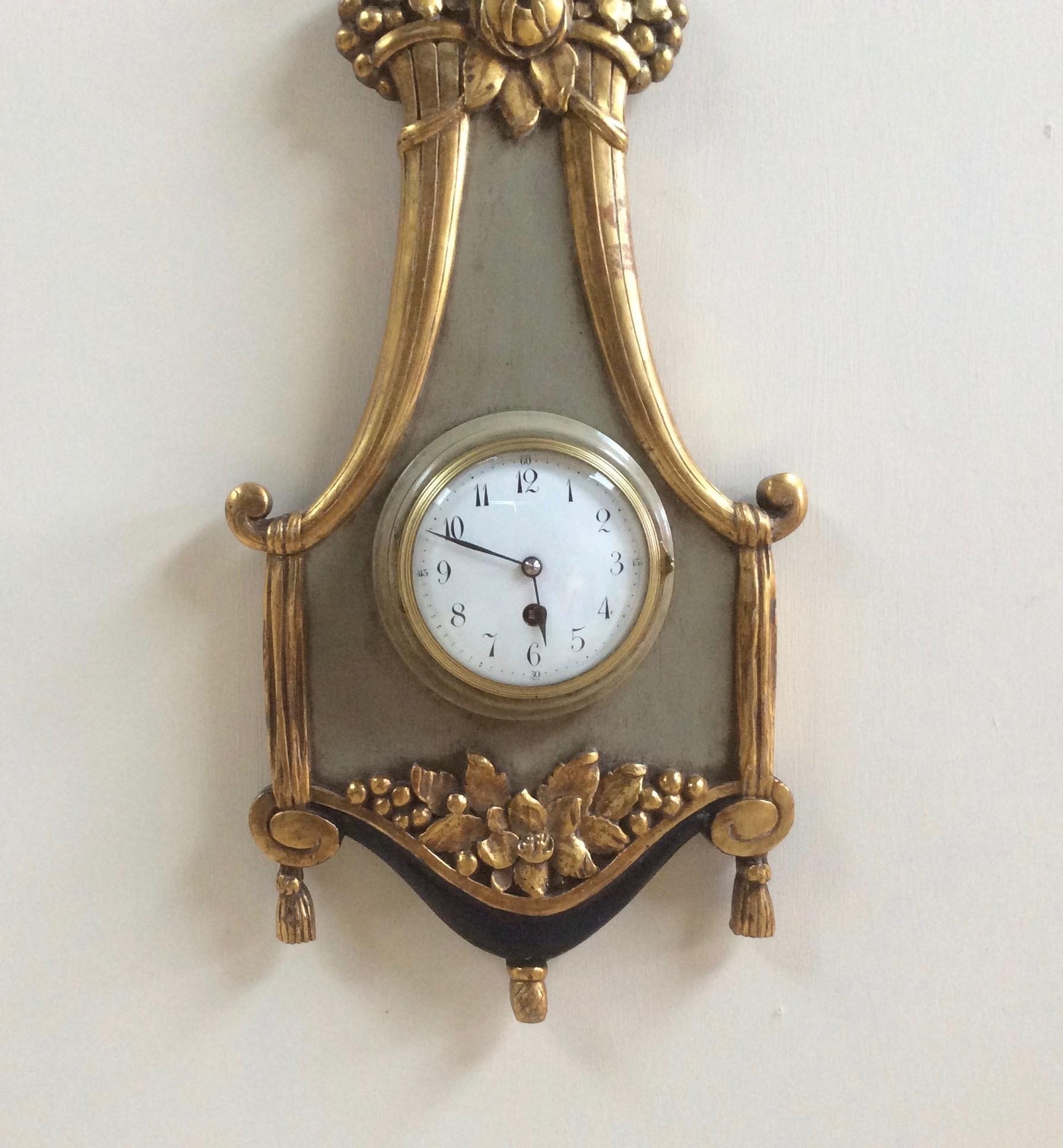French wall clock on a grey ground with beautifully carved gilded foliate decoration surmounted by a gilded bow.

Enamel dial with Arabic numerals and original ‘Blued’ steel hands.

Eight day movement with platform escapement, circa 1920.
  