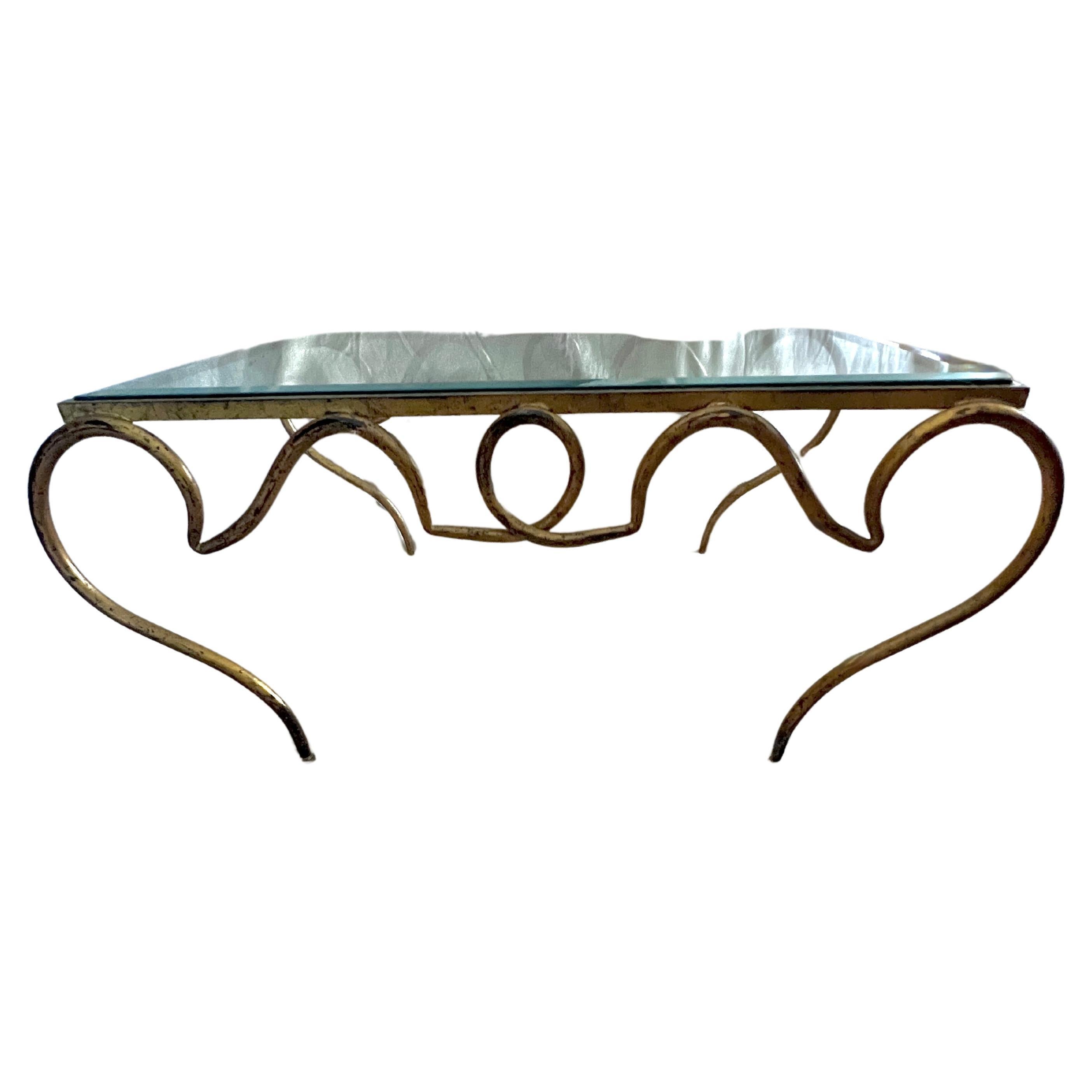 Stunning and elegant, this Rene Prou Scroll coffee table is a timeless piece.  While designed in the ca. 1940's the table is still relevant and sophisticated today.  Hand Forged wrought iron that has been gold leafed, making it chic for any living