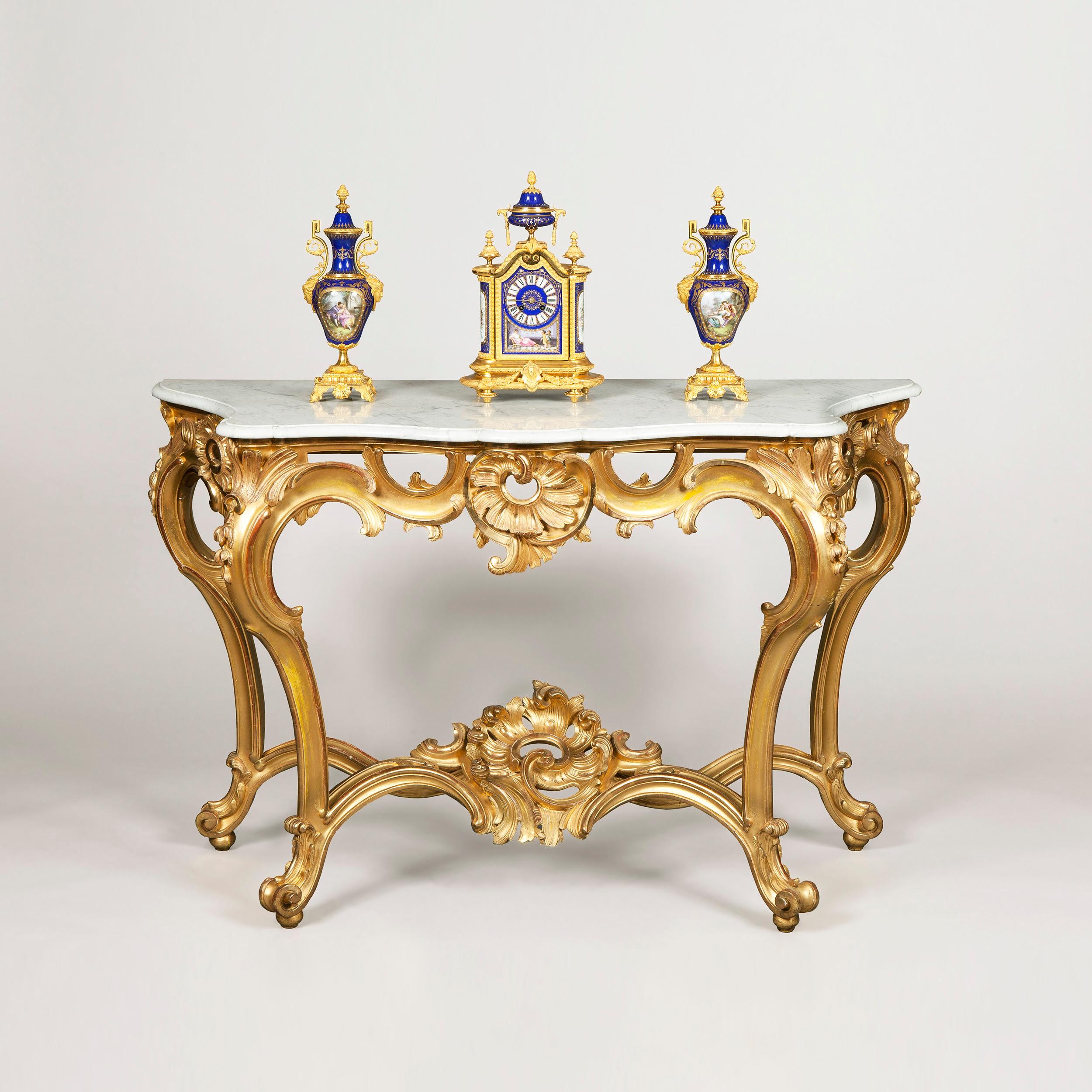 A console table in the Louis XV manner.

Constructed in carved gold leaf giltwood, with a Carrara marble platform; rising from scrolled toes, having hipped cabriole legs, conjoined with stylised ‘X’ form arced under stretchers issuing from a central