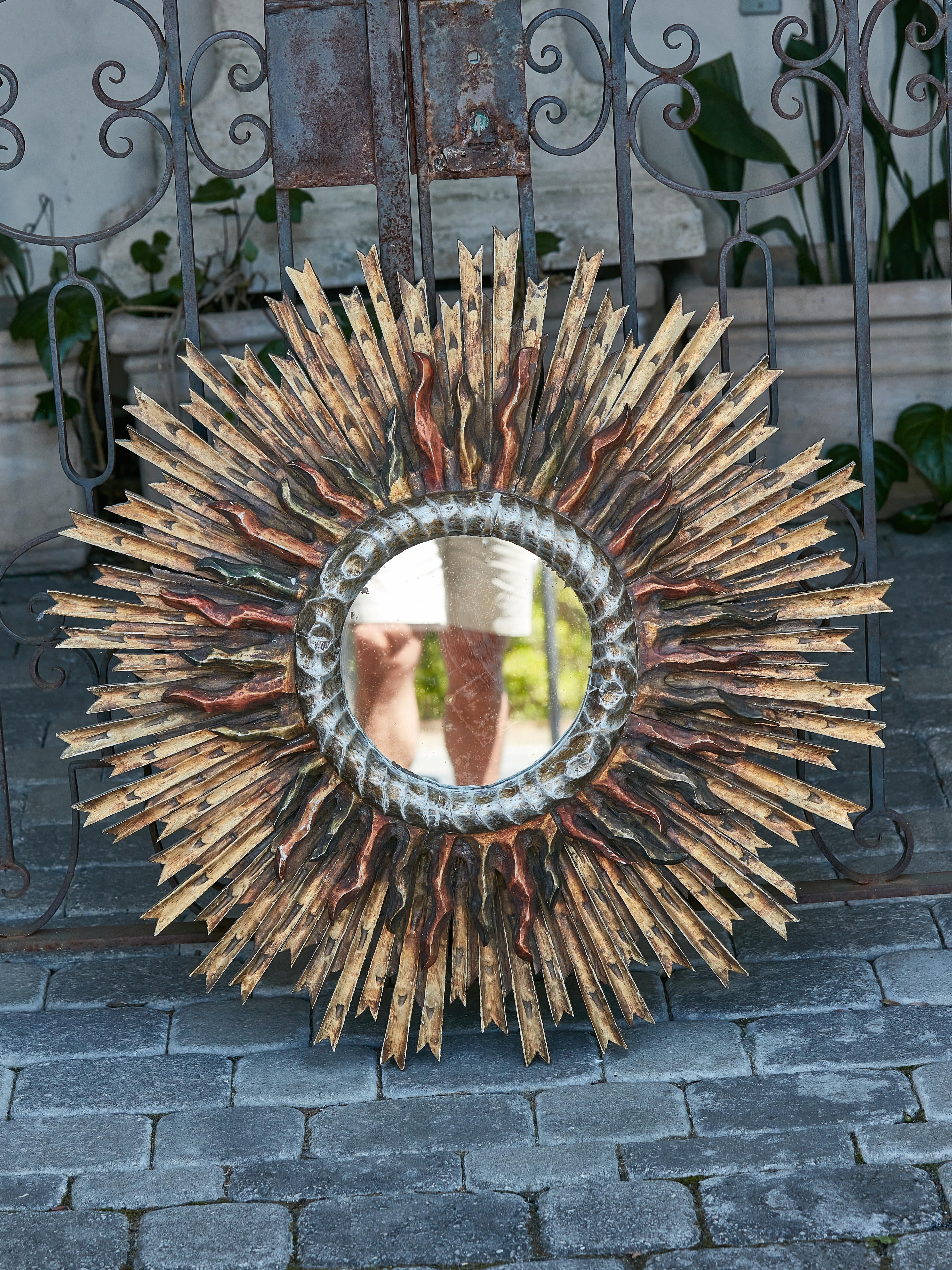 A French Midcentury sunburst two-layer mirror with polychrome accents. Radiating with a celestial charm, this French Midcentury Sunburst Mirror is an ethereal vision that transports one to the heavens. Embodying the vibrant energies of the sun, the