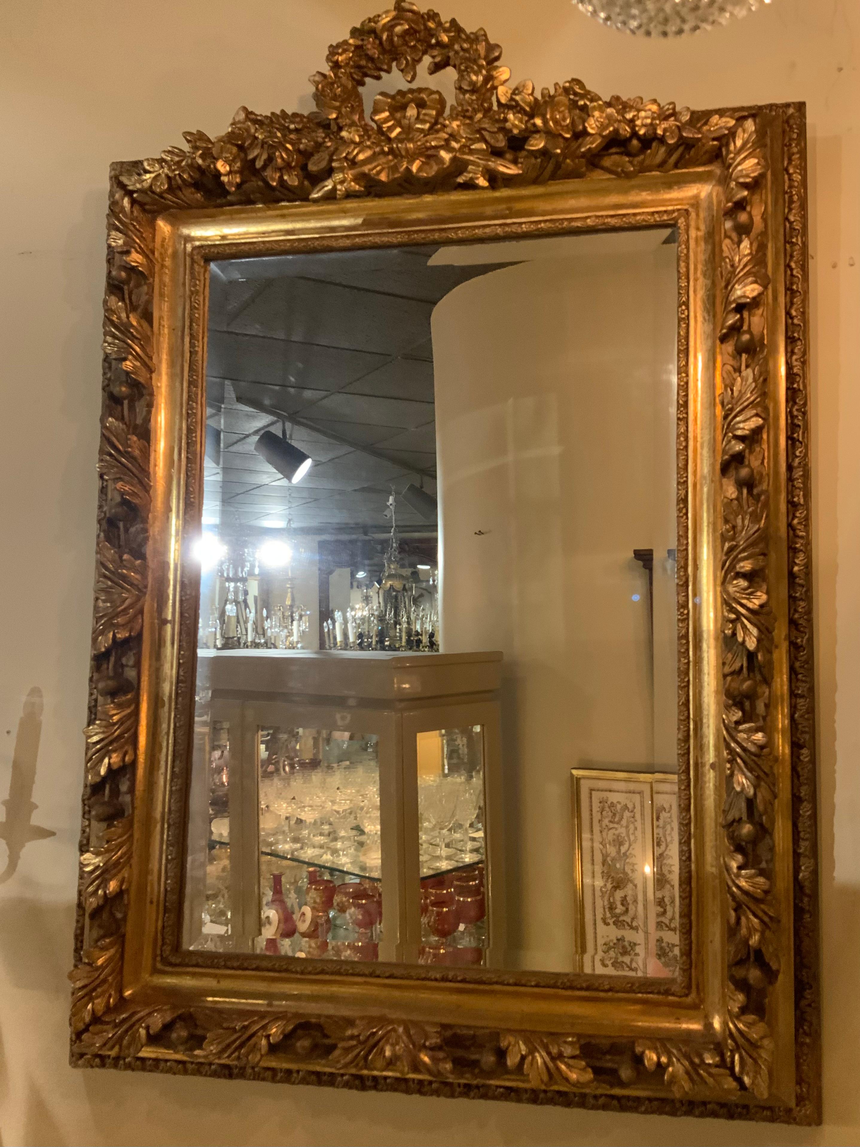Giltwood with a floral wreath form  crest with floral sprays and a
Central ribbon bow not, the outer frame deeply molded with
Leaf and acorn motifs and set with a beveled plate glass mirror.