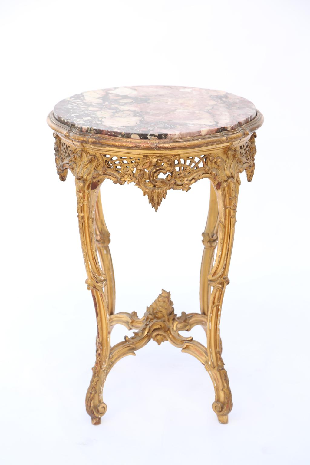 Rococo table, having a round top of rouge marble, on carved giltwood base, its pierced, reticulated apron decorated with C-scrolls and combing, raised on shaped, hock-legs, joined by channelled stretcher, centered by foliate-carved accents, ending